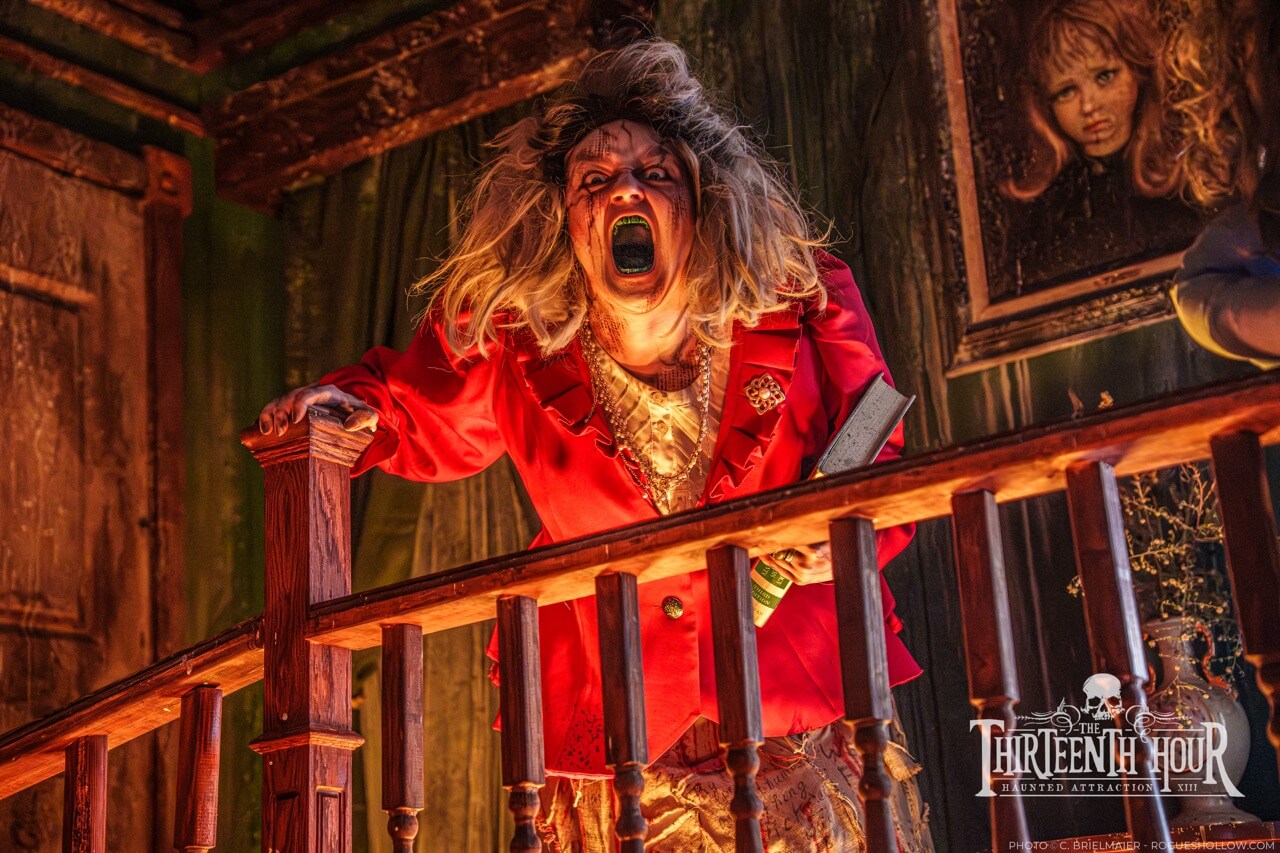 Screaming scare actor in a red jacket leaning over a staircase