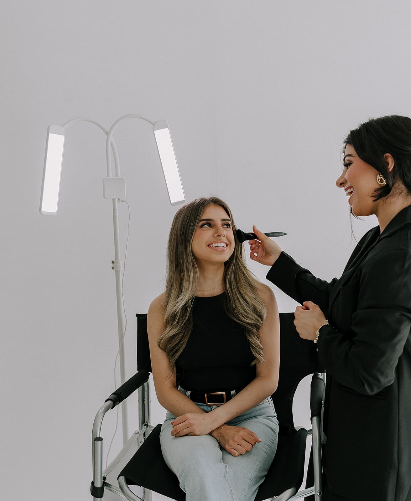 Haley Gould applies makeup to a client under studio lighting, highlighting the versatility of Revelator Studio for beauty shoots in Shreveport.