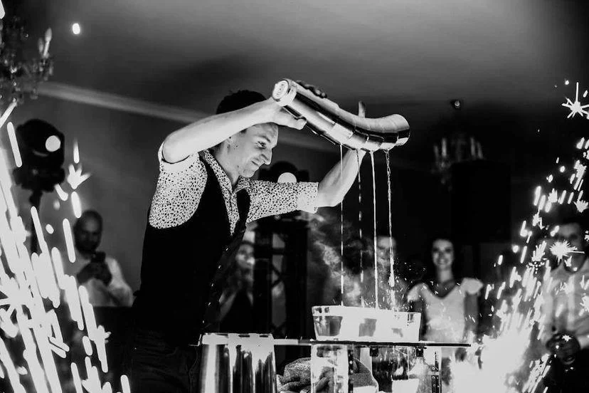 Barman na weselu pokazuje sztuczki barmańskie przed zgromadzonymi gośćmi podczas pokazu barmańskiego