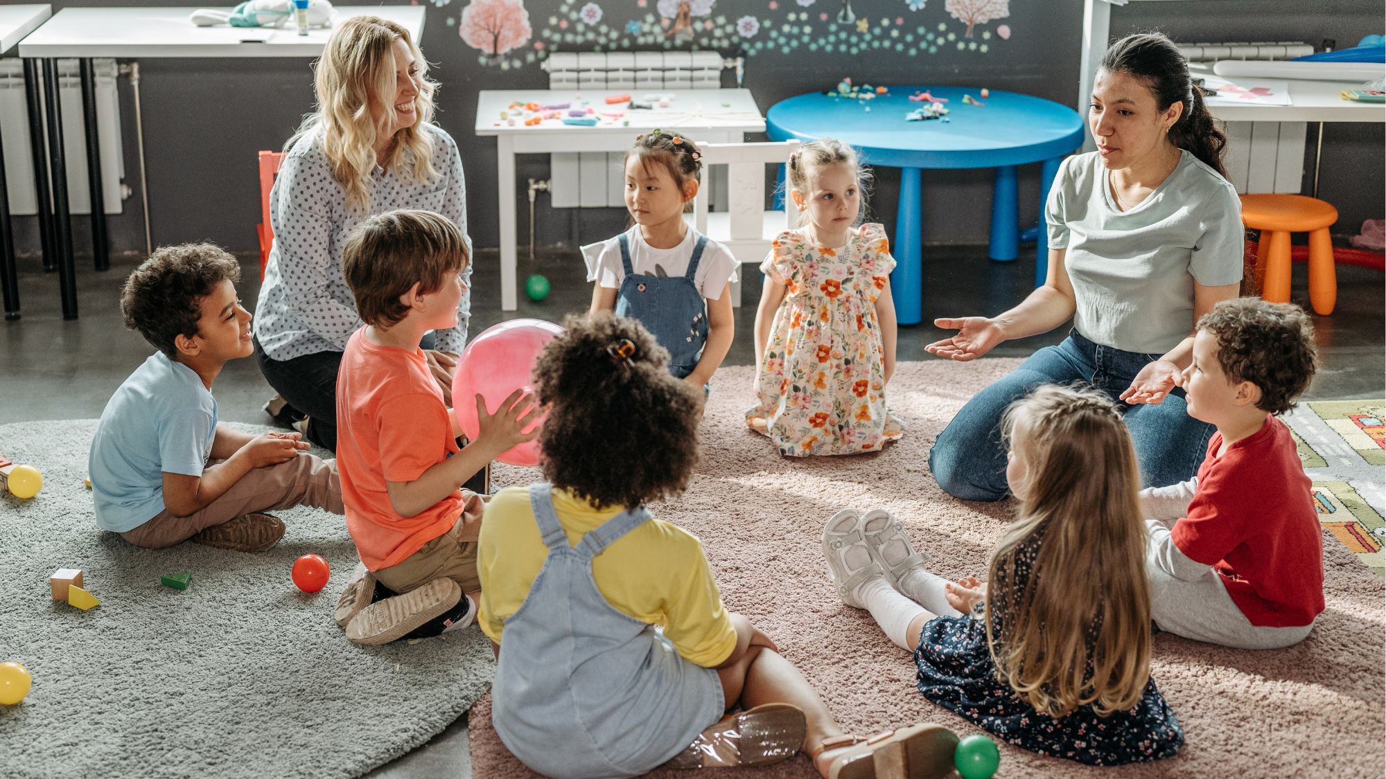 A group of children and two teachers sitting in a circle using toys