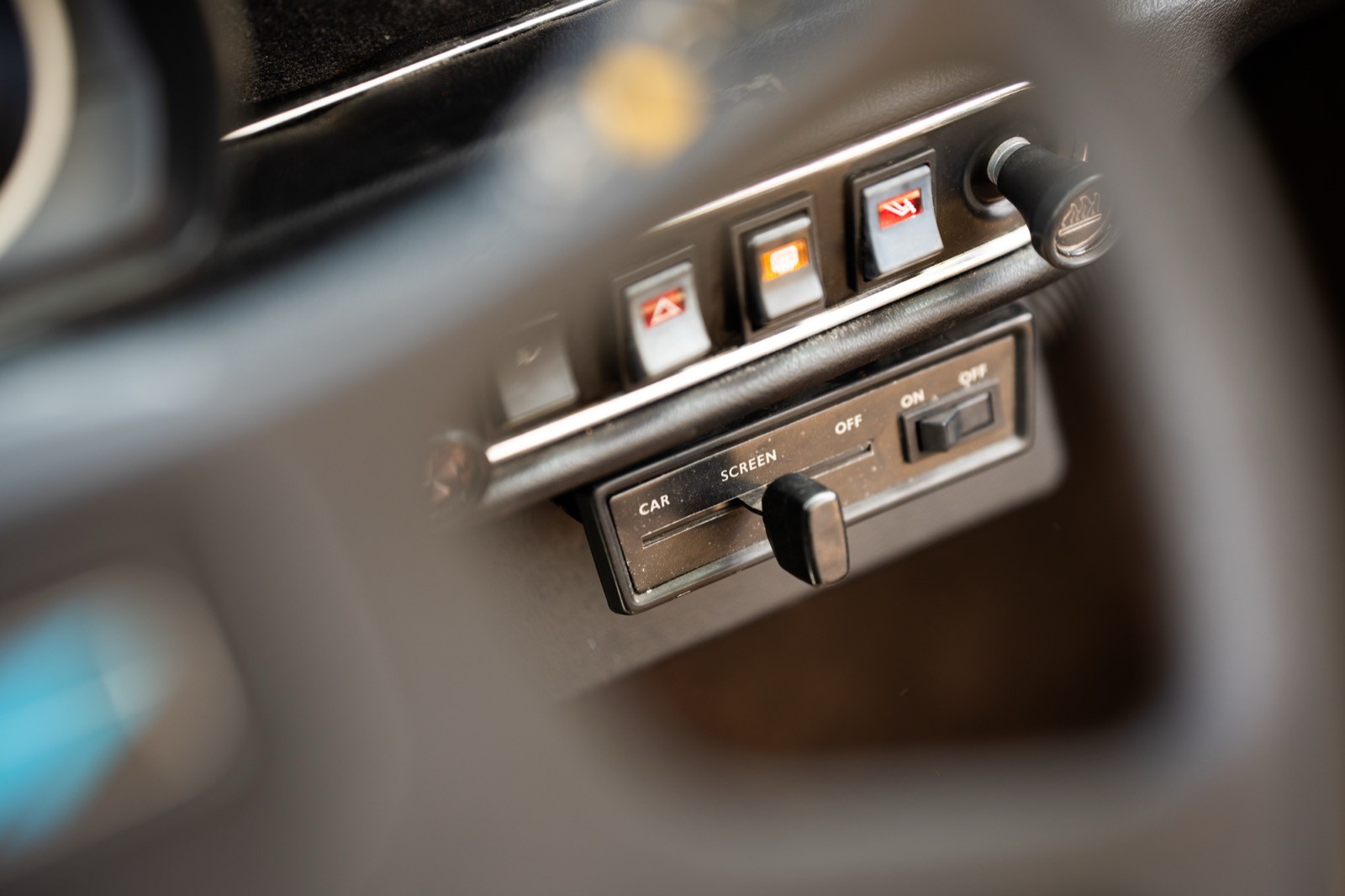 Close-up of a car's dashboard controls, featuring toggle switches and a sleek design.