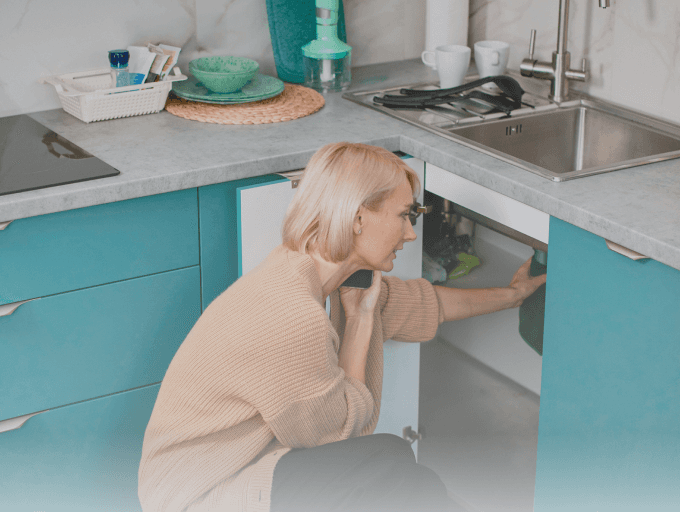 A woman checking a water leak in the kitchen