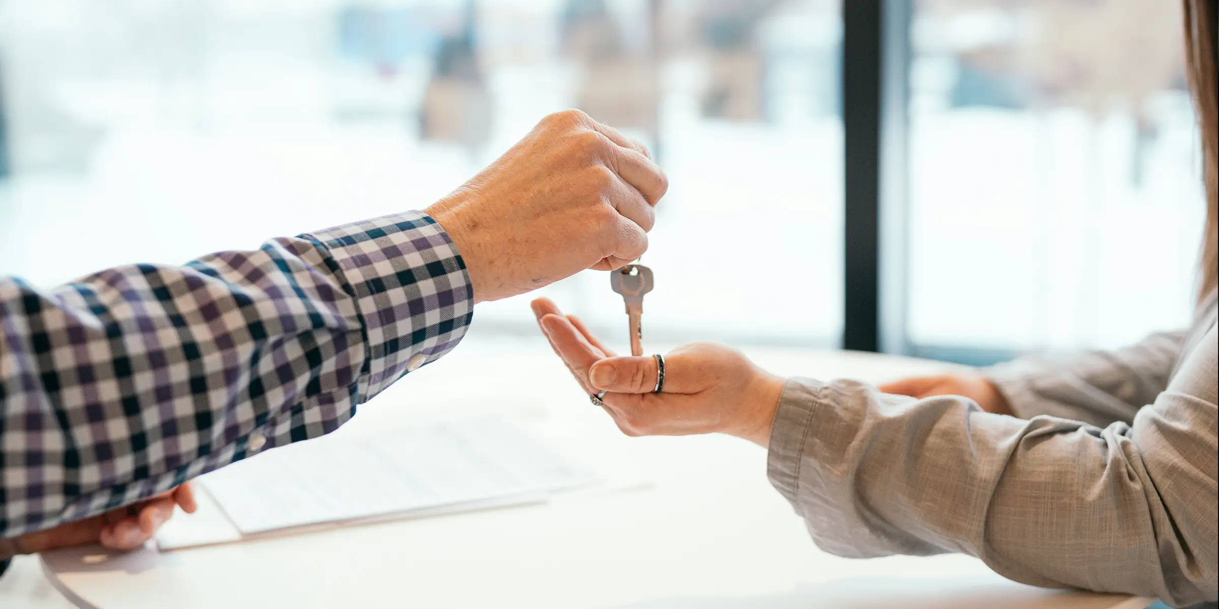 Close-up of one person handing house keys to another, symbolising handover or ownership.