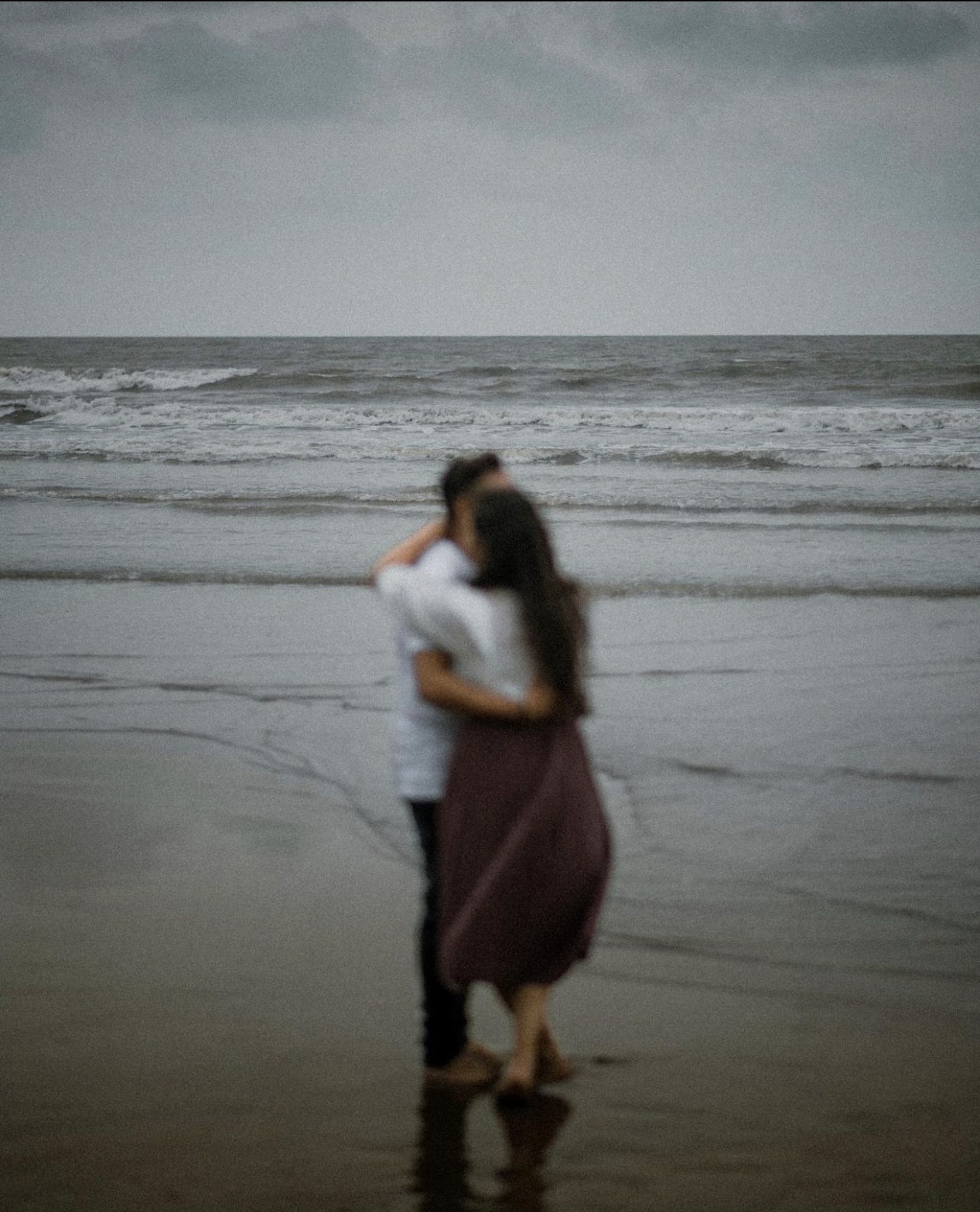 A couple embraces lovingly on a wooden dock.