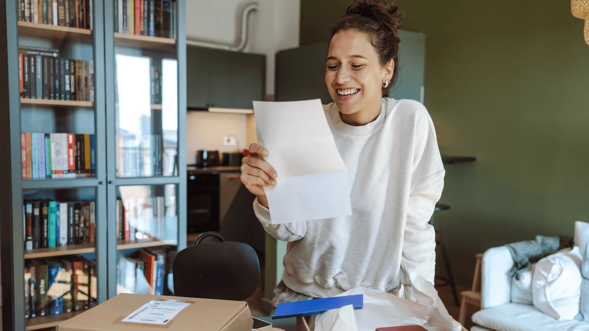 A woman, in her living room, reads a piece of paper