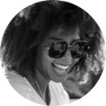 Natalie, 38, laughing in black and white outdoor portrait with sunglasses for customer testimonial