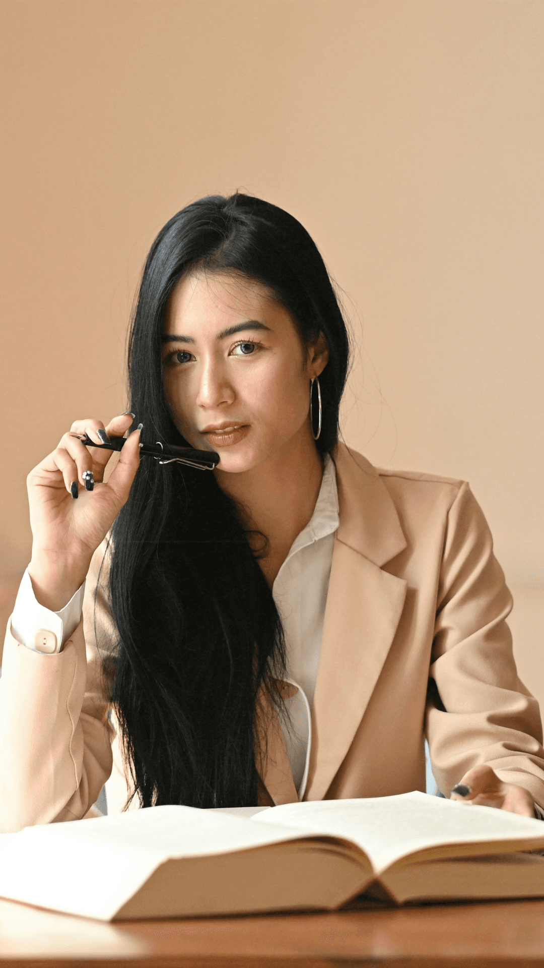 Writer at desk with open book in soft neutral light.