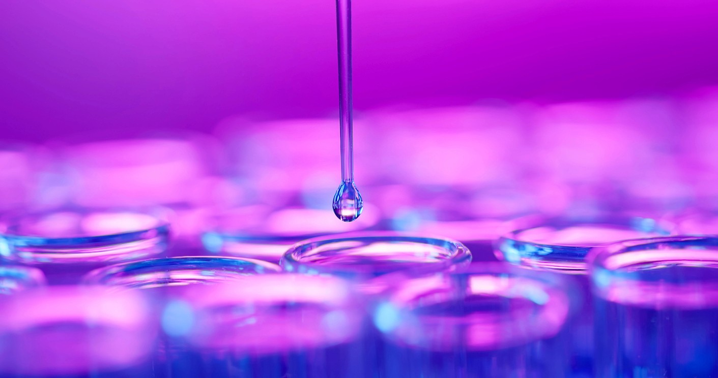 A medical dropper adding solution to a group of test tubes