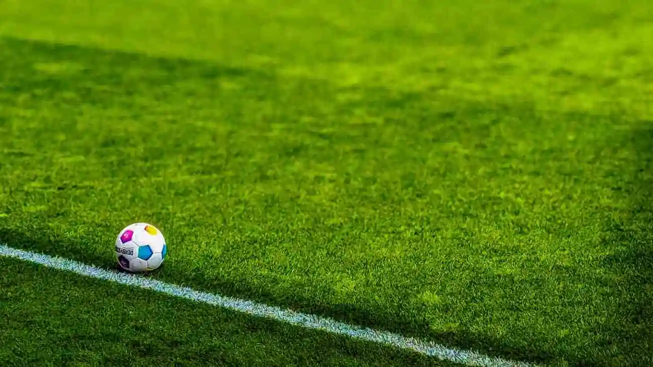 A football lies on the grass line of a football pitch, ready for the next game.