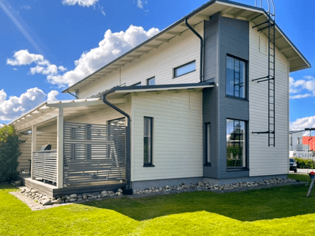 Ulkomaalattu moderni paritalo Seinäjoella, vaaleanharmaa julkisivu tummilla yksityiskohdilla, hoidettu nurmikkoalue