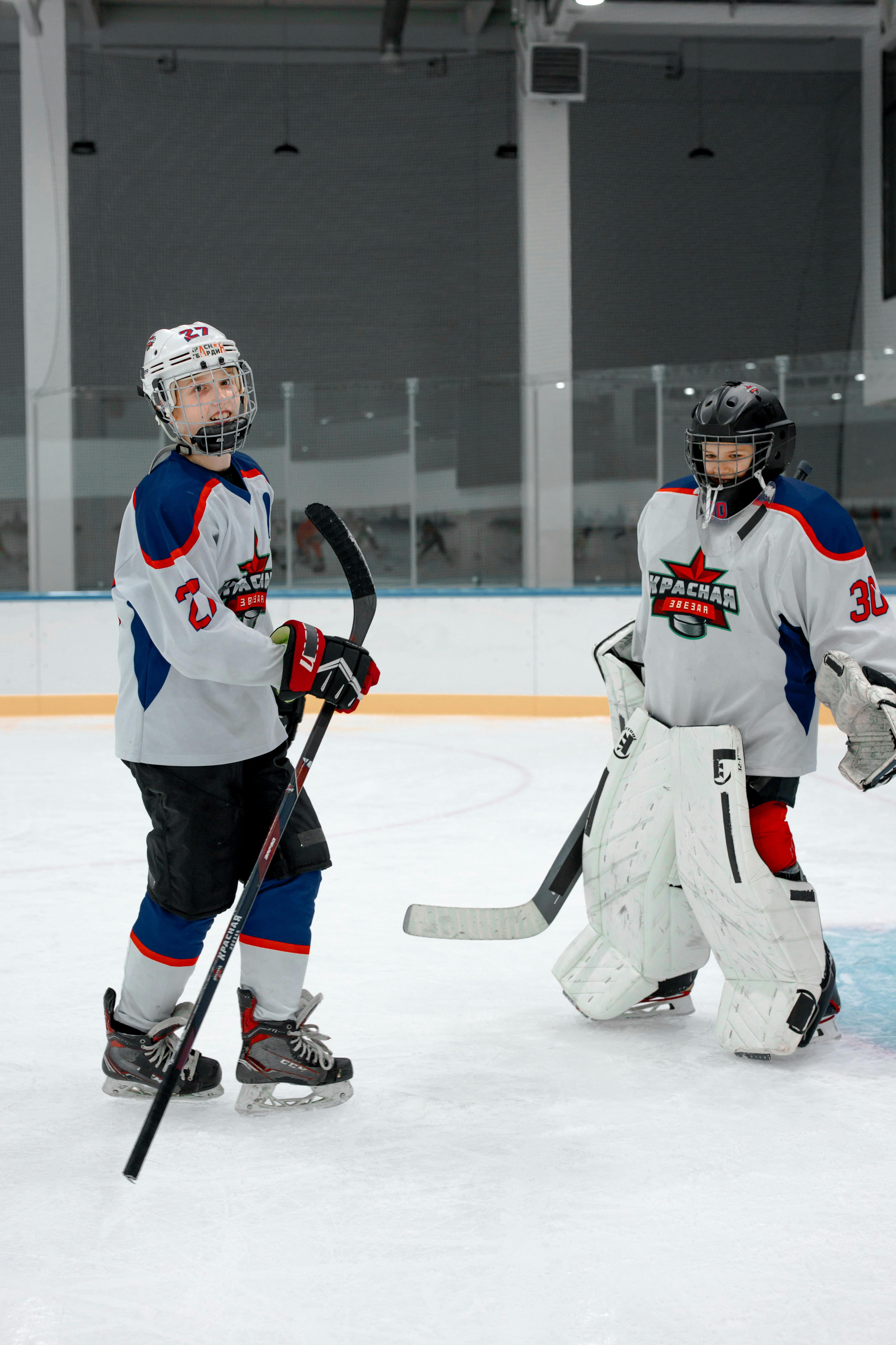 A female ice hockey player and goalie smiling