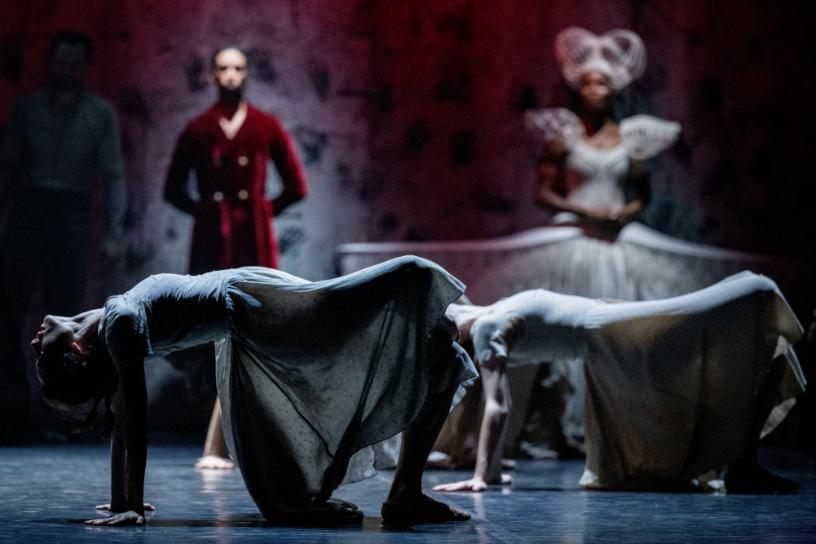 Dancers in dramatic backbends on a dark stage in Akram Khans Giselle.