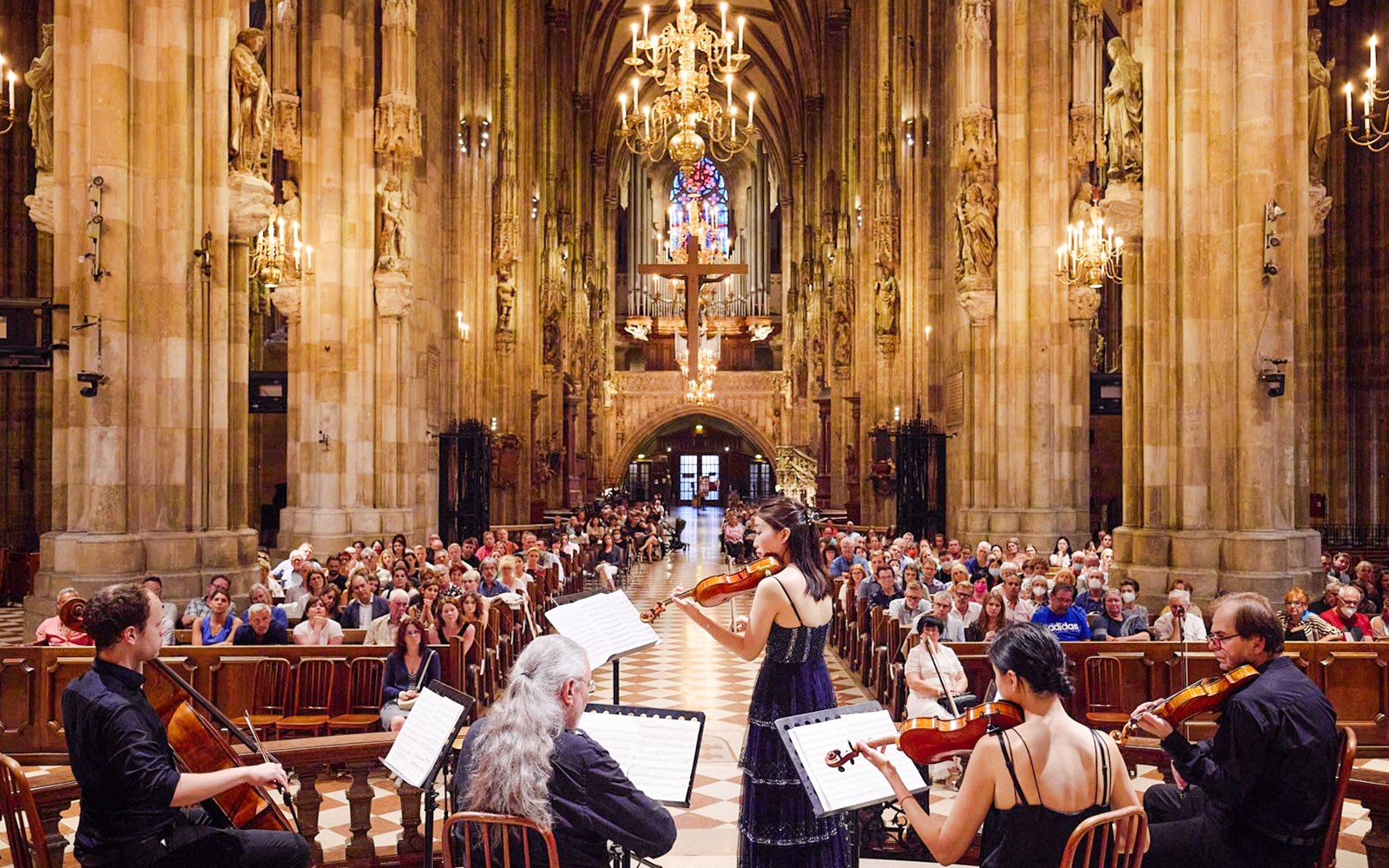 Orchestra performing inside St. Stephen's Cathedral, Vienna, with audience seated.