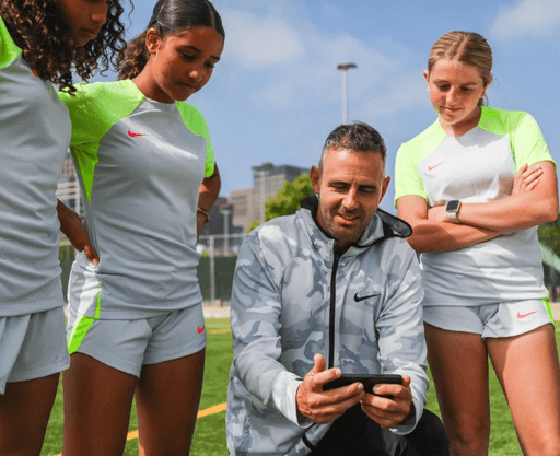 Soccer coach showing game footage on a smartphone to youth players, highlighting Reeplayer’s mobile app for reviewing game recordings