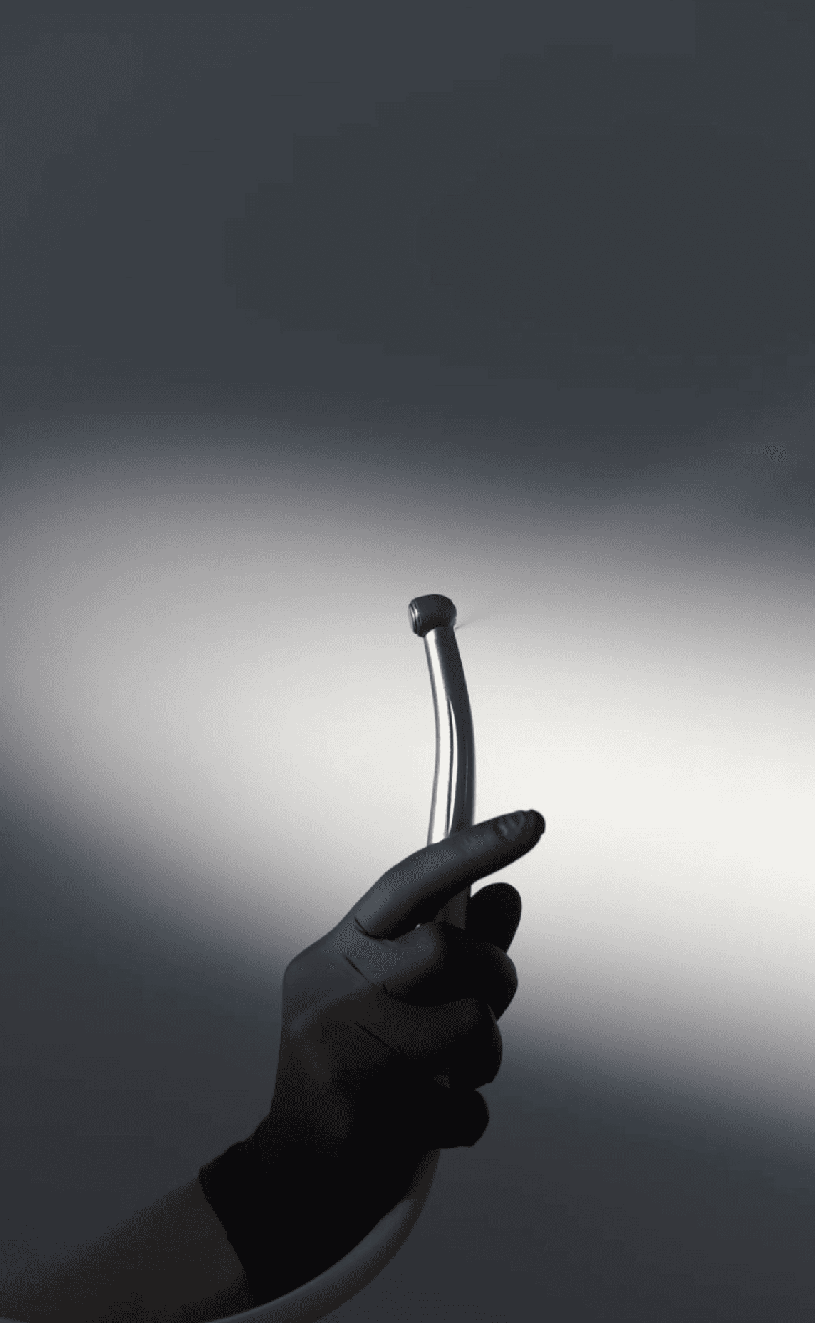 Hand in schwarzer Handschuh hält zahnärztliches Handstück mit Saugfunktion