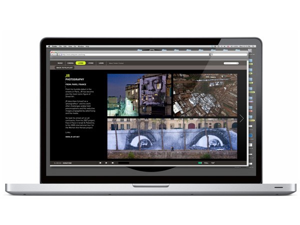 A silver Apple MacBook laptop is open, displaying a webpage titled “JR PHOTOGRAPHY” from french.FRANCE. The page includes text on the left and a collage of images on the right. The collage includes two large eye images and a mural-like artwork below. The laptop is positioned against a white background.