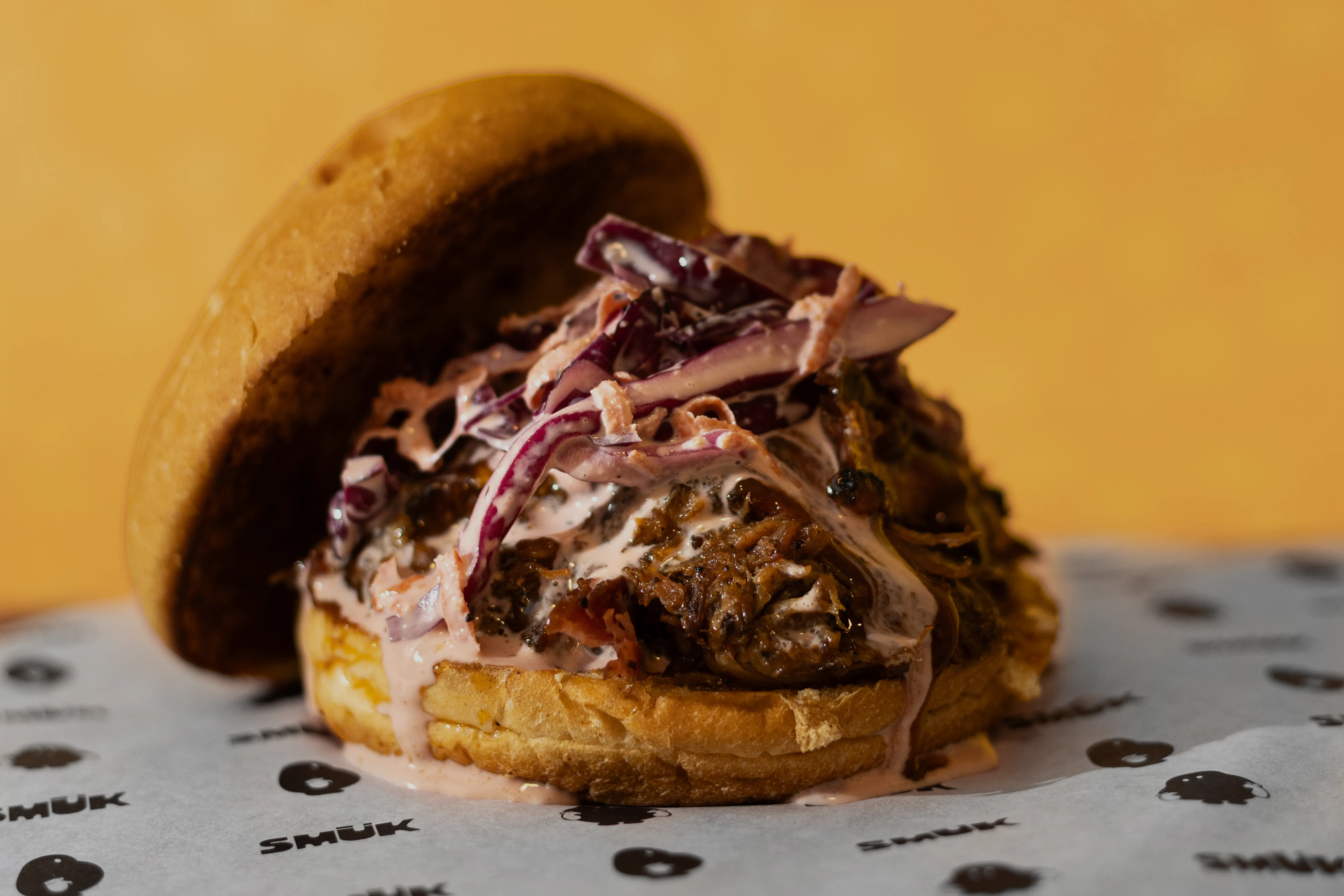 Hamburguesa de pulled pork con fondo amarillo cálido