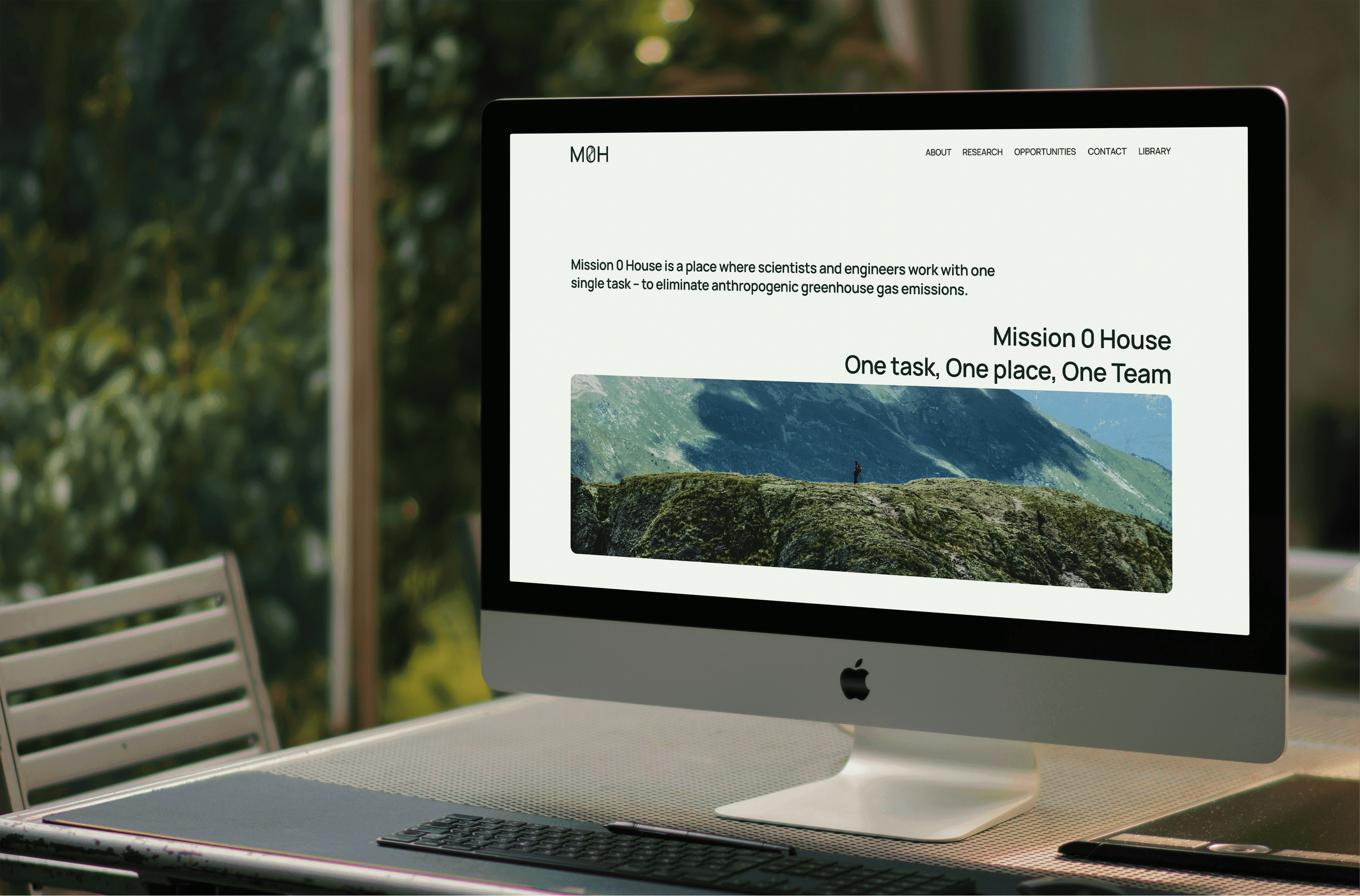 Mac screen showcasing the website, it is located on a desk