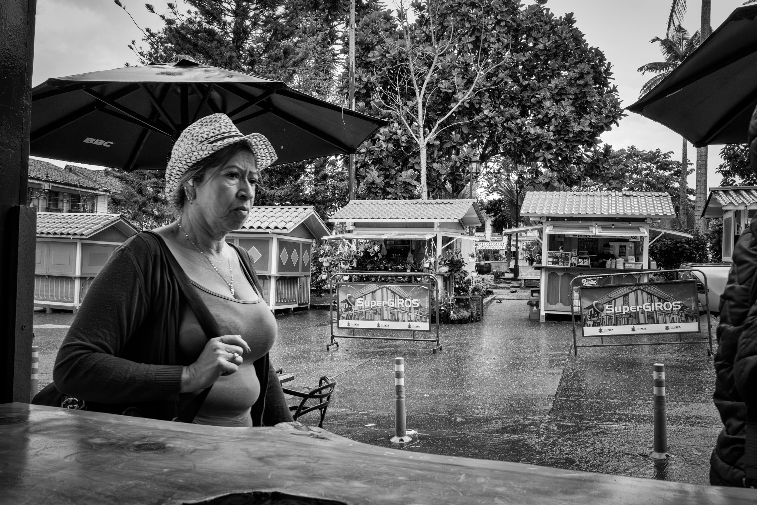 Rainy street scene with people passing by a bar window.