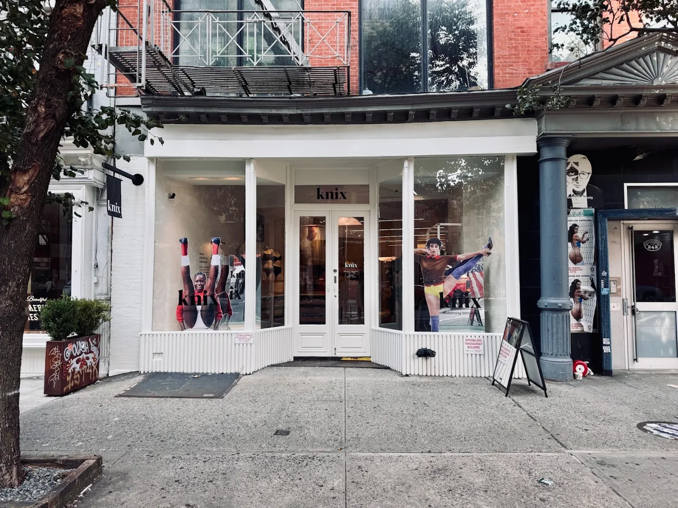 Knix New York retail storefront featuring large window graphics and projecting flag sign on SoHo street corner.