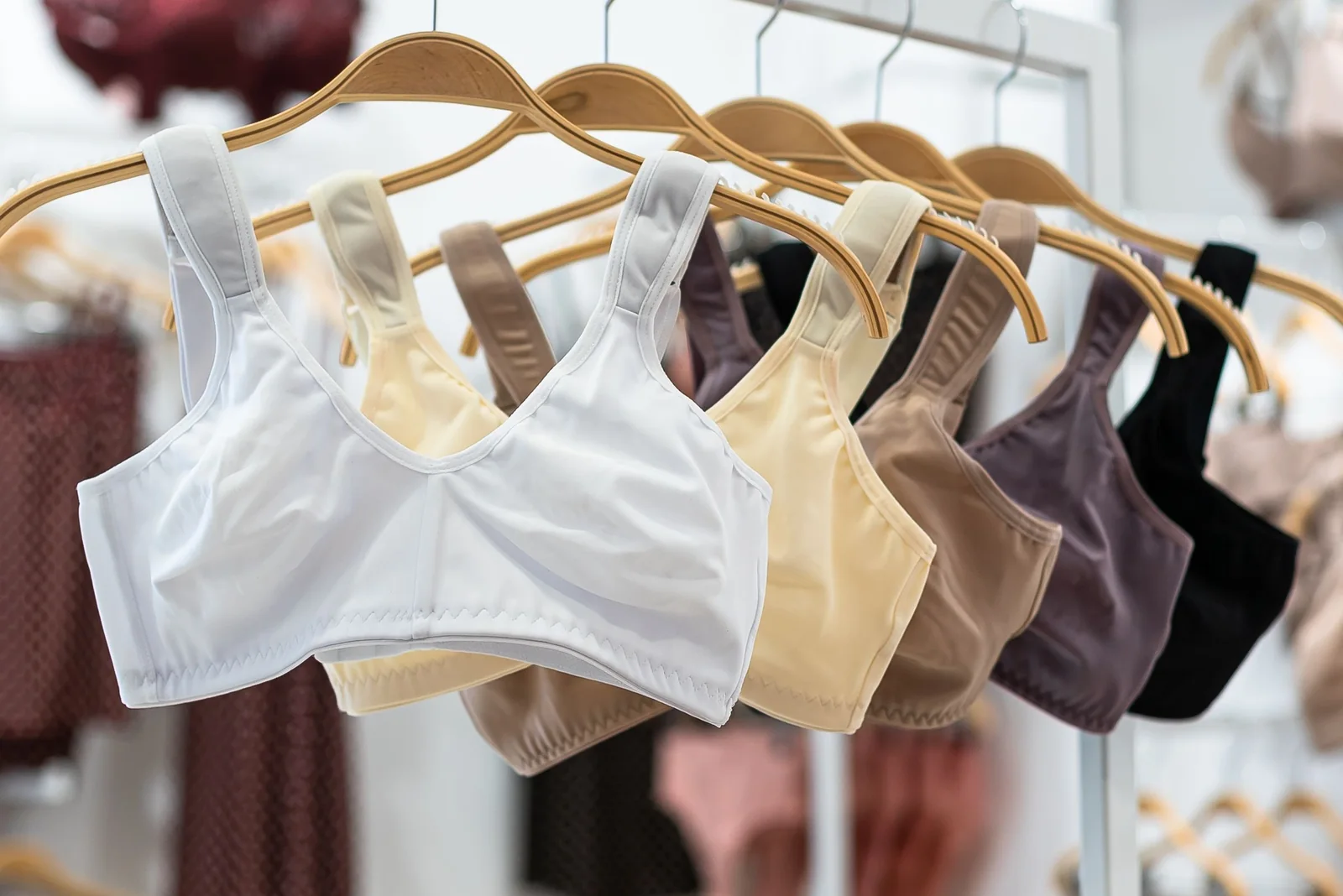 Neutral-colored athletic apparel displayed on wooden hangers.