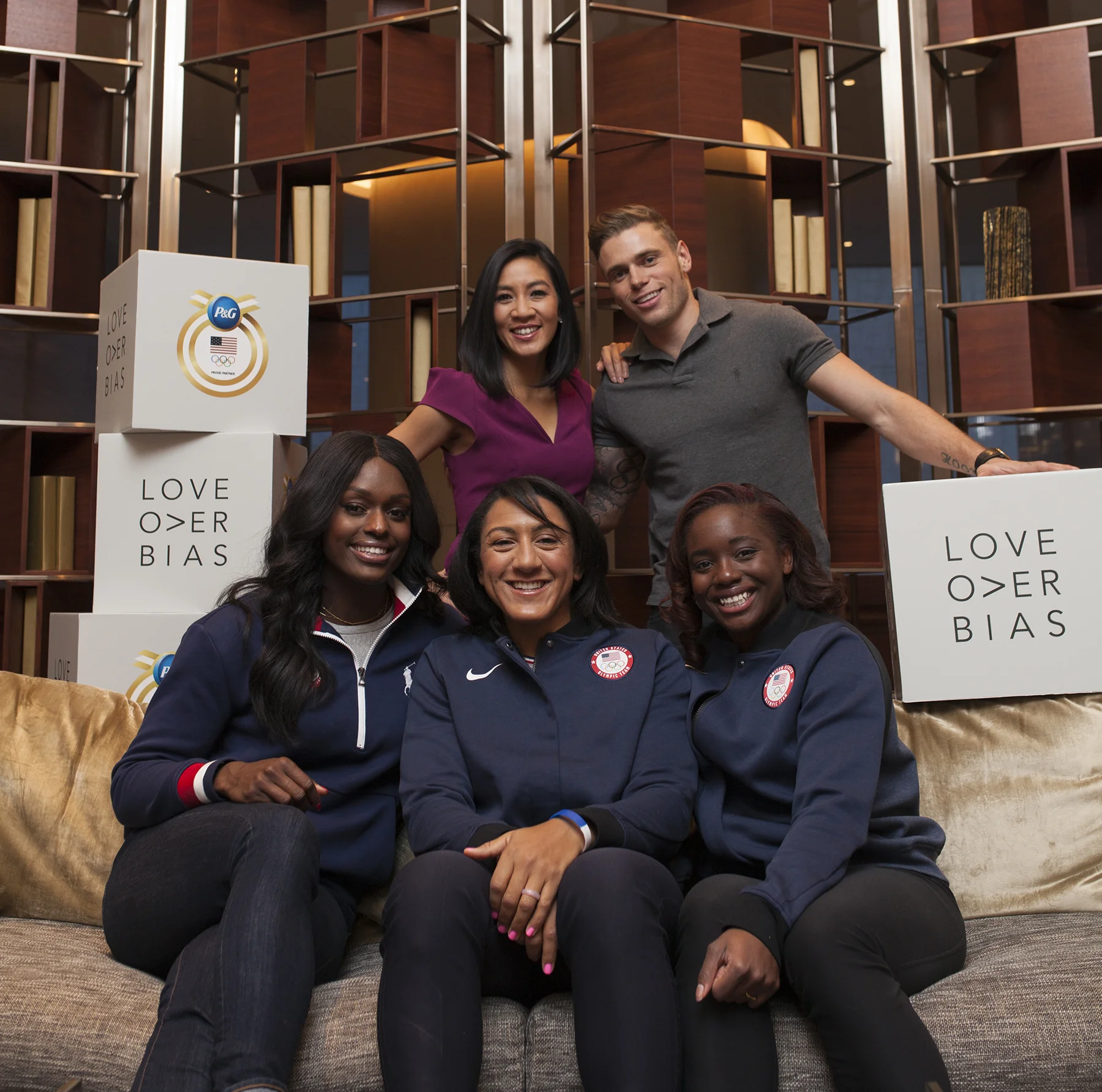 Original campaign event photograph with athletes and white Love Over Bias cubes featuring P&G and Olympic branding