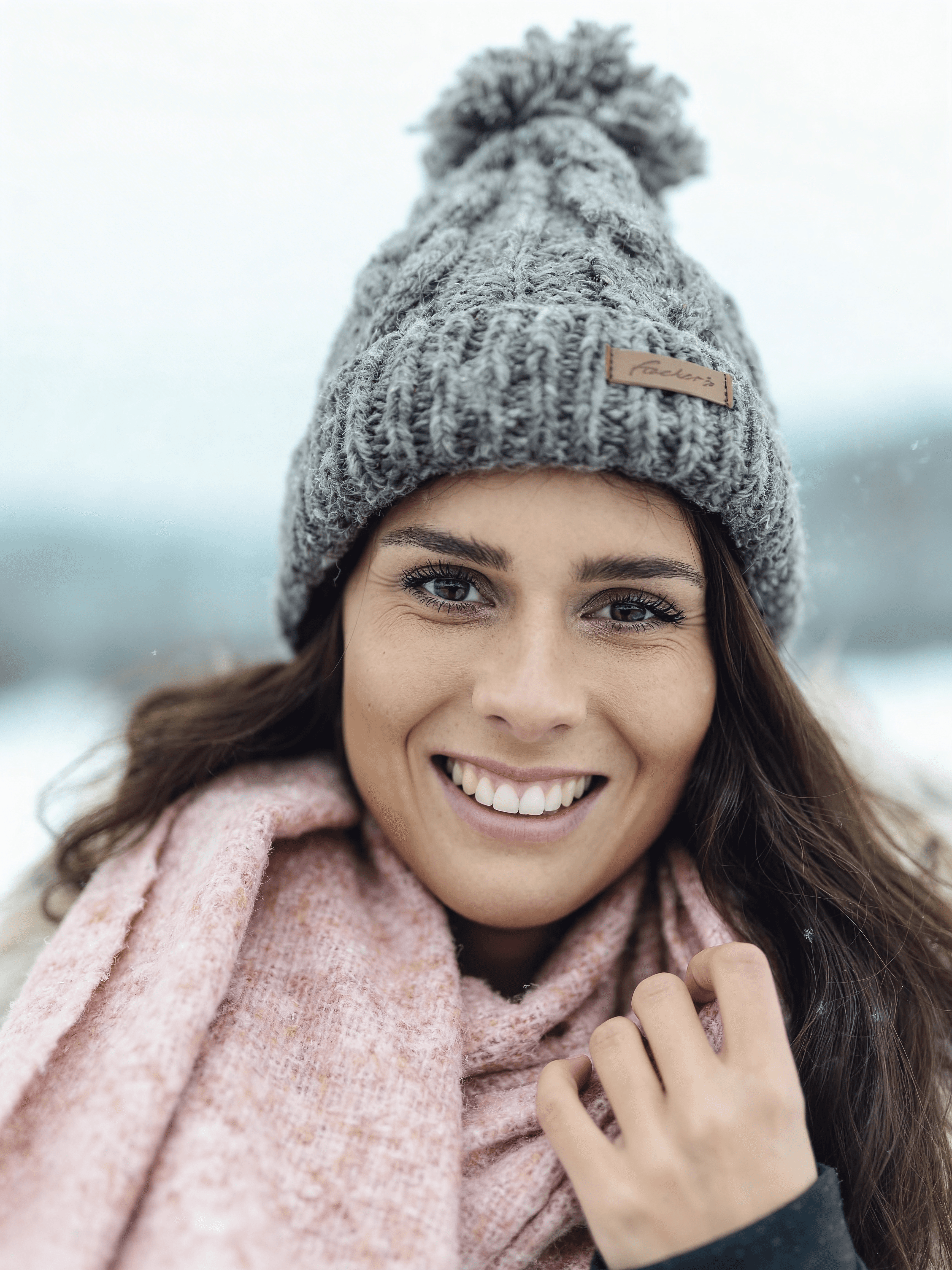 KI-Model in schwarzem Top und Bikini am sonnigen Strand, natürliche Pose mit erhobenem Arm, weiches Abendlicht und ruhige Meereskulisse