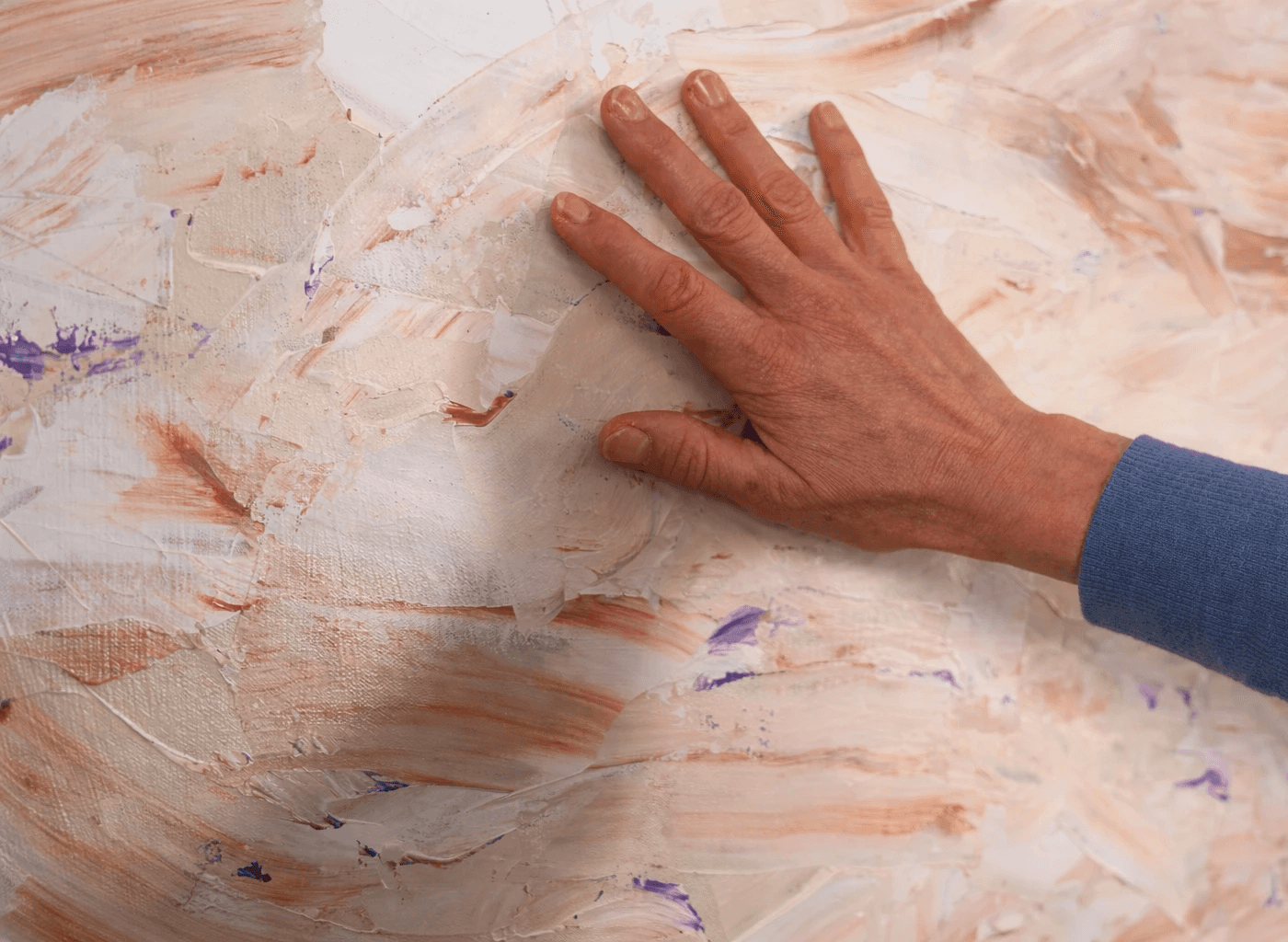 Künstlerhand arbeitet an abstraktem Gemälde auf Leinwand im Atelier