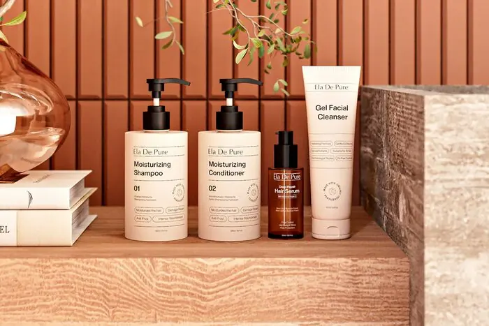 A lineup of shampoo, conditioner and treatment bottles on a wooden shelf against a terracotta wall