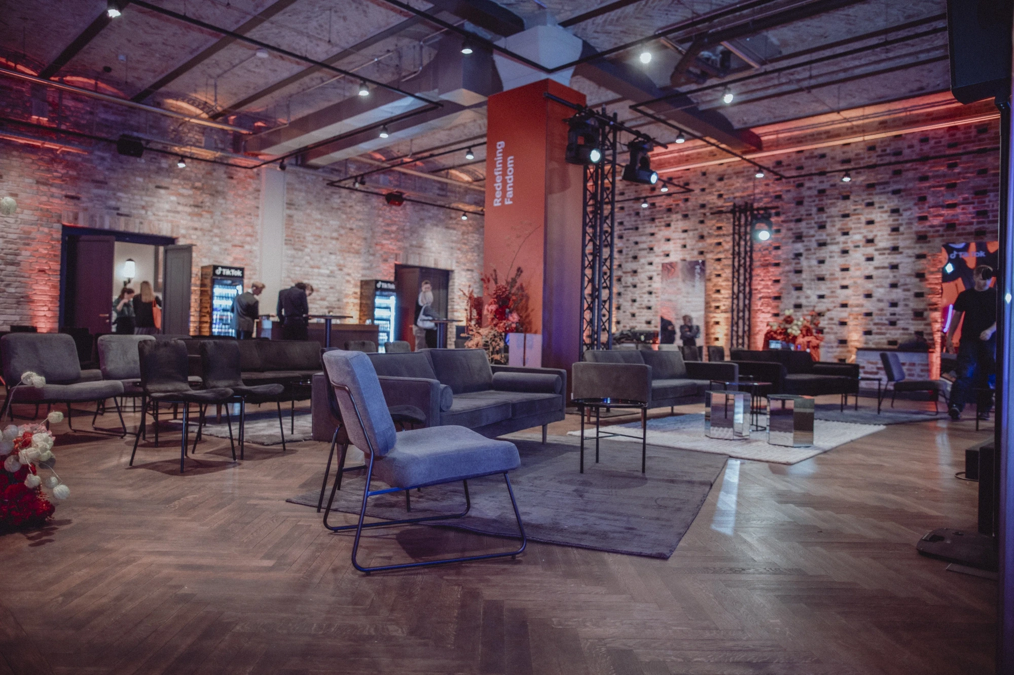 Loft event space with grey sofas, terracotta pillar and warm-lit brick walls at the TikTok Summit.