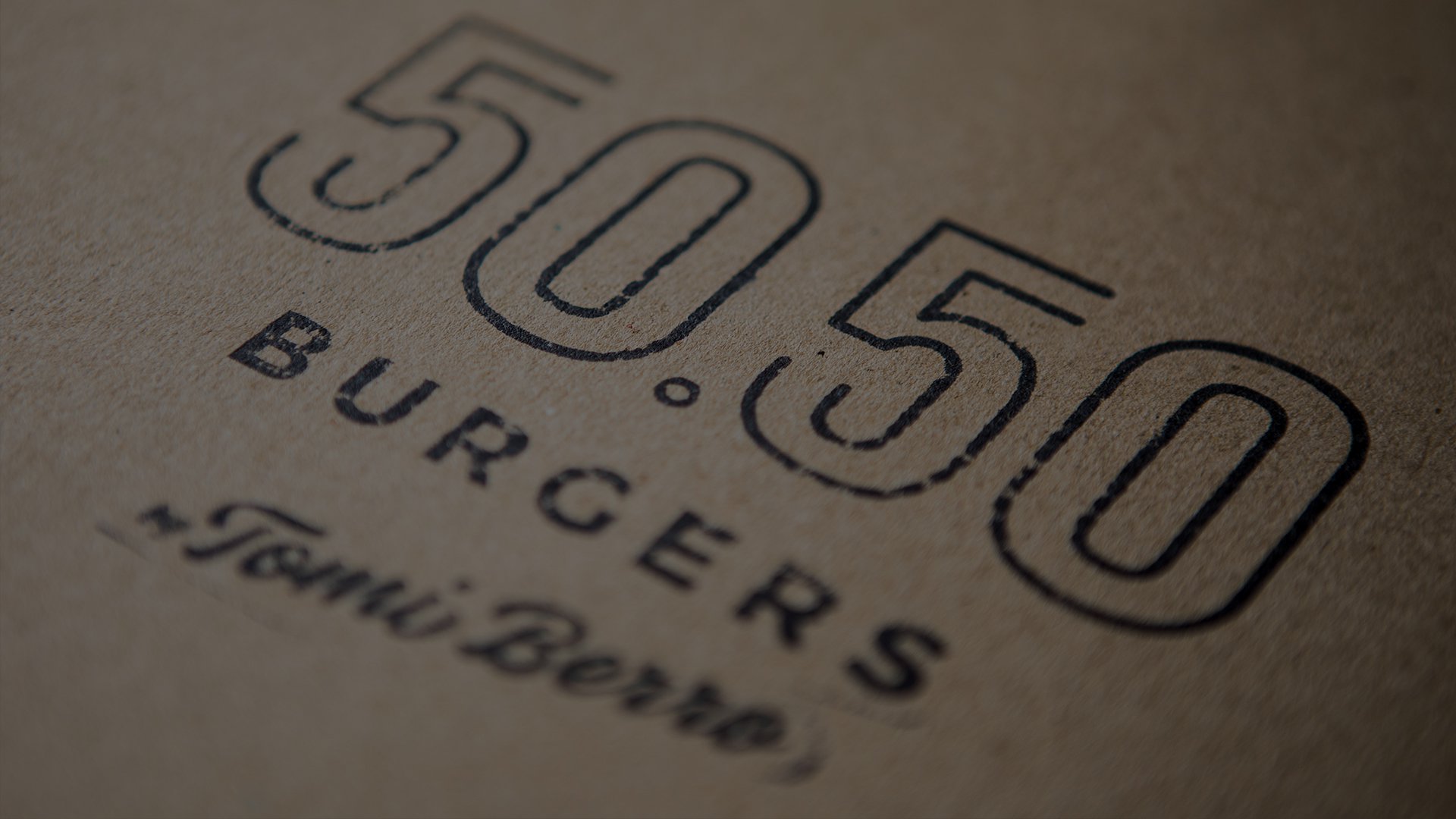 Text on a beige background reads "50.50 Burgers by Tomi Brrr" in bold, black letters. The style is minimalist, creating a modern, rustic feel.