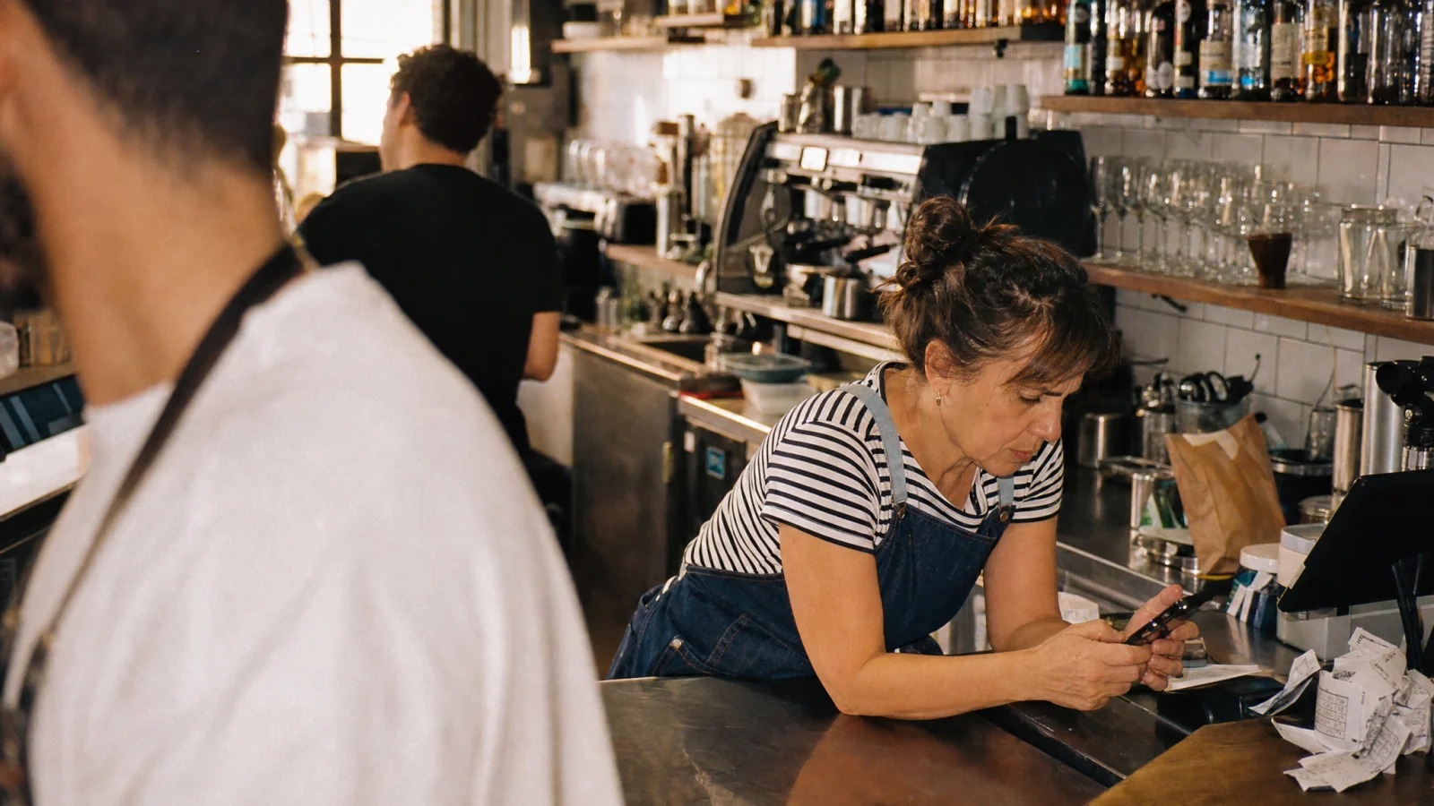 Responsabile allarga con le dita un menu in PDF sul telefono al banco del bar