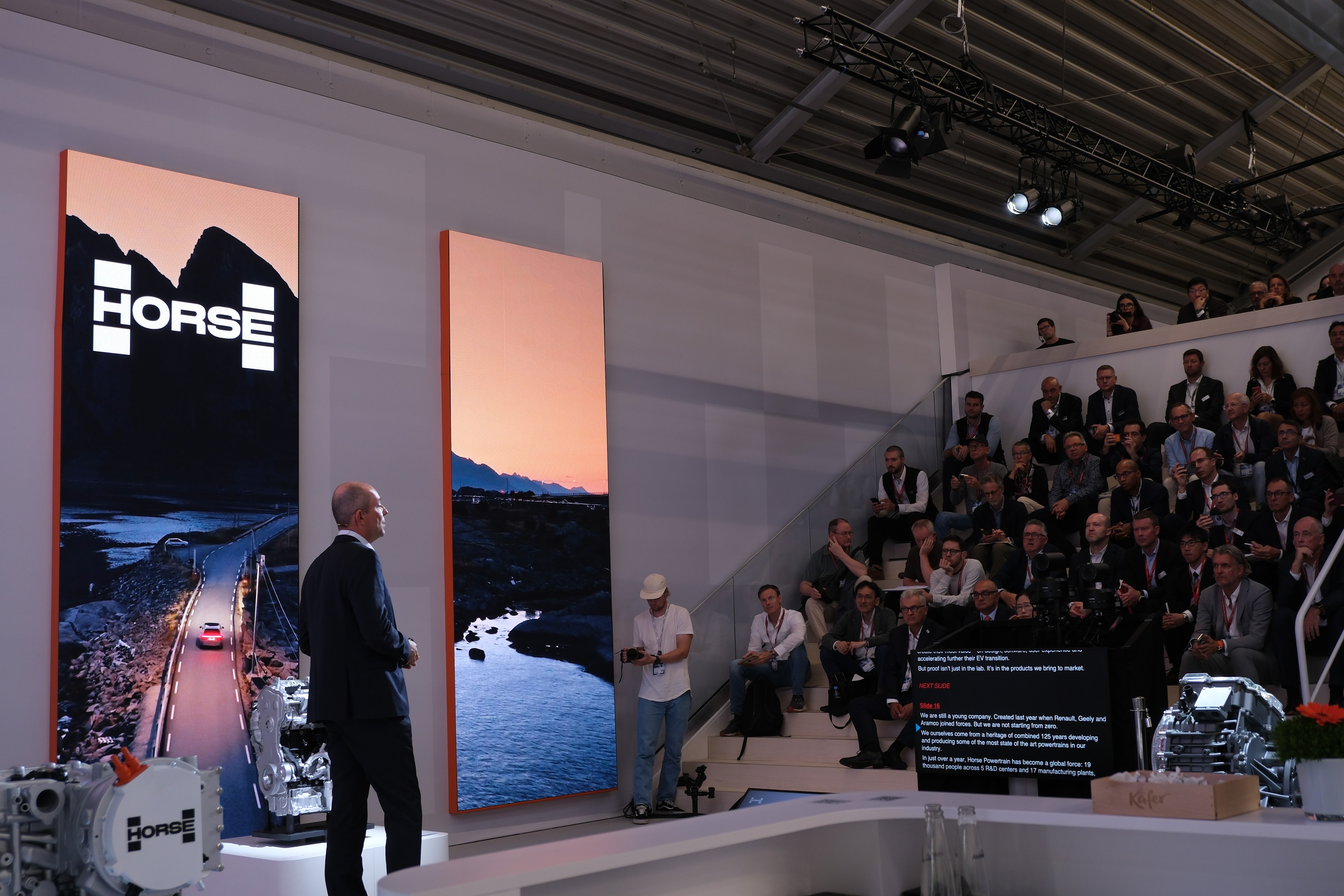 presentatör som står på en scen och talar inför en publik