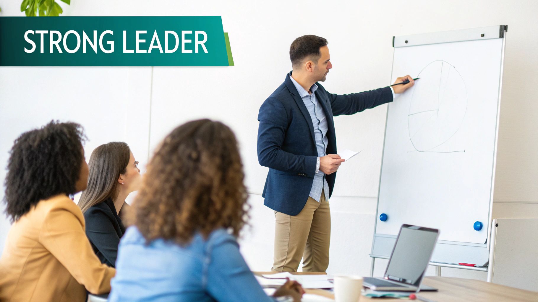 A strong male leader presents a pie chart on a whiteboard to an attentive diverse audience.