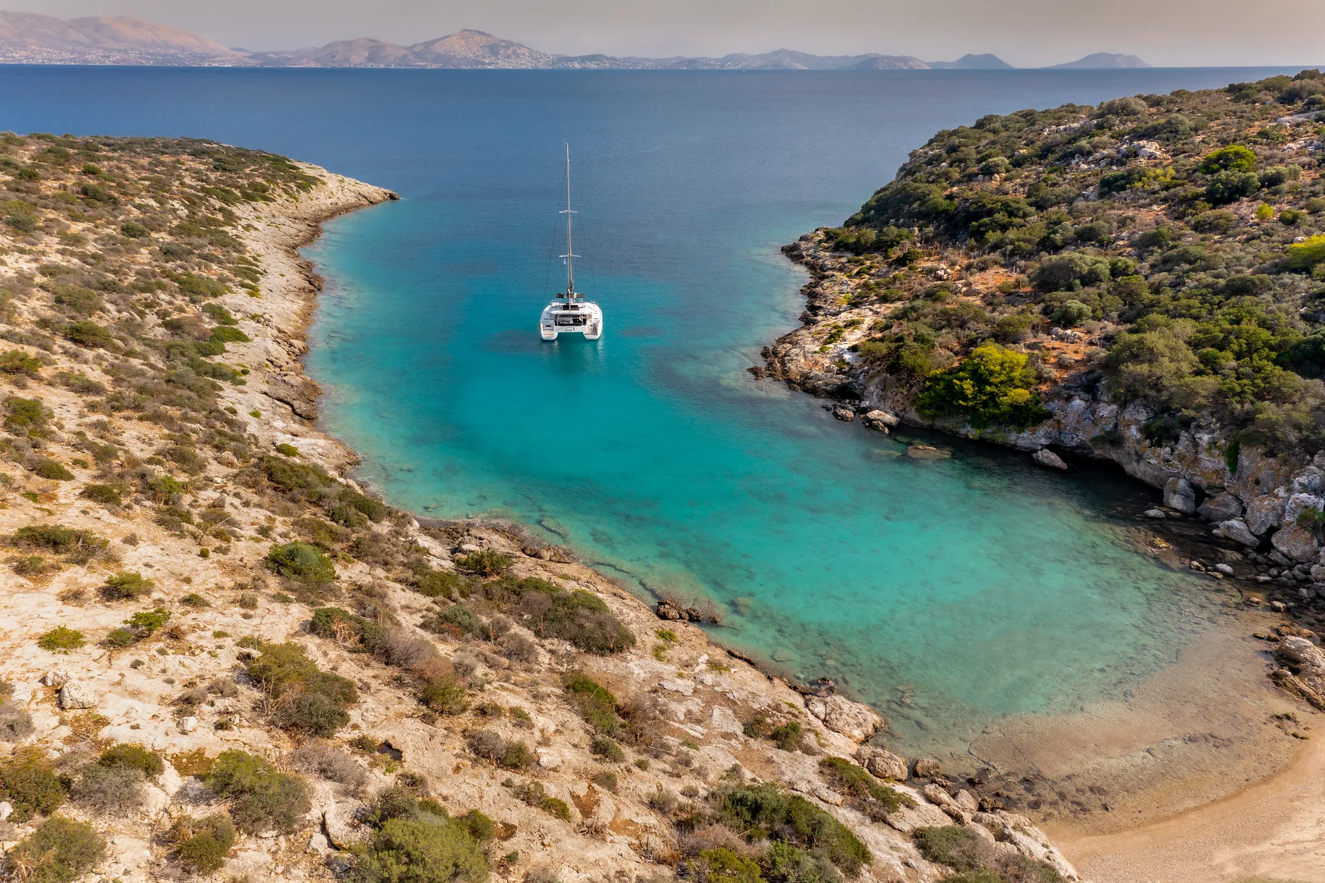 White Rock 36 speedboat with captain at helm cruising calm blue waters near Paros coastline with hills in background.