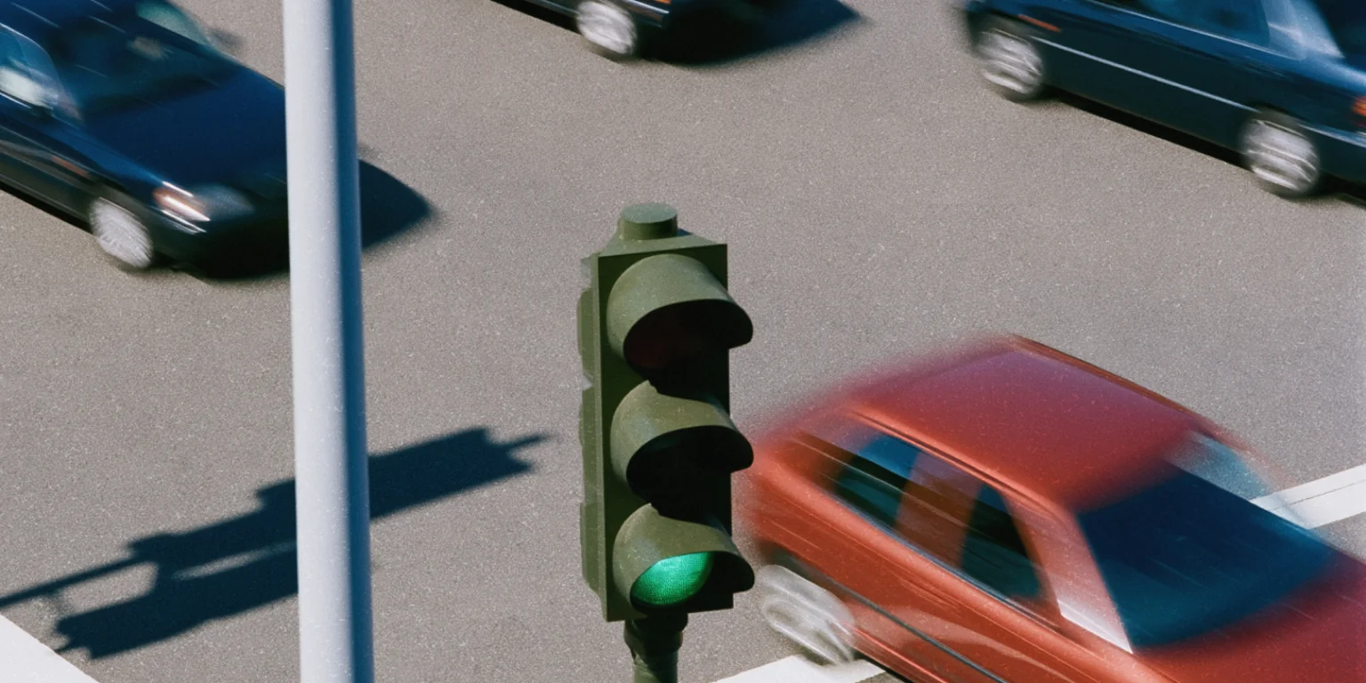Green traffic light above cars moving through an intersection.