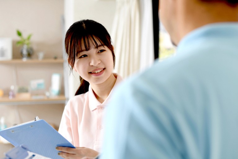 A young woman smiling and holding a book or binder while having a meeting with another person