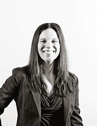 A black and white photo of a smiling woman, dressed in a suit.