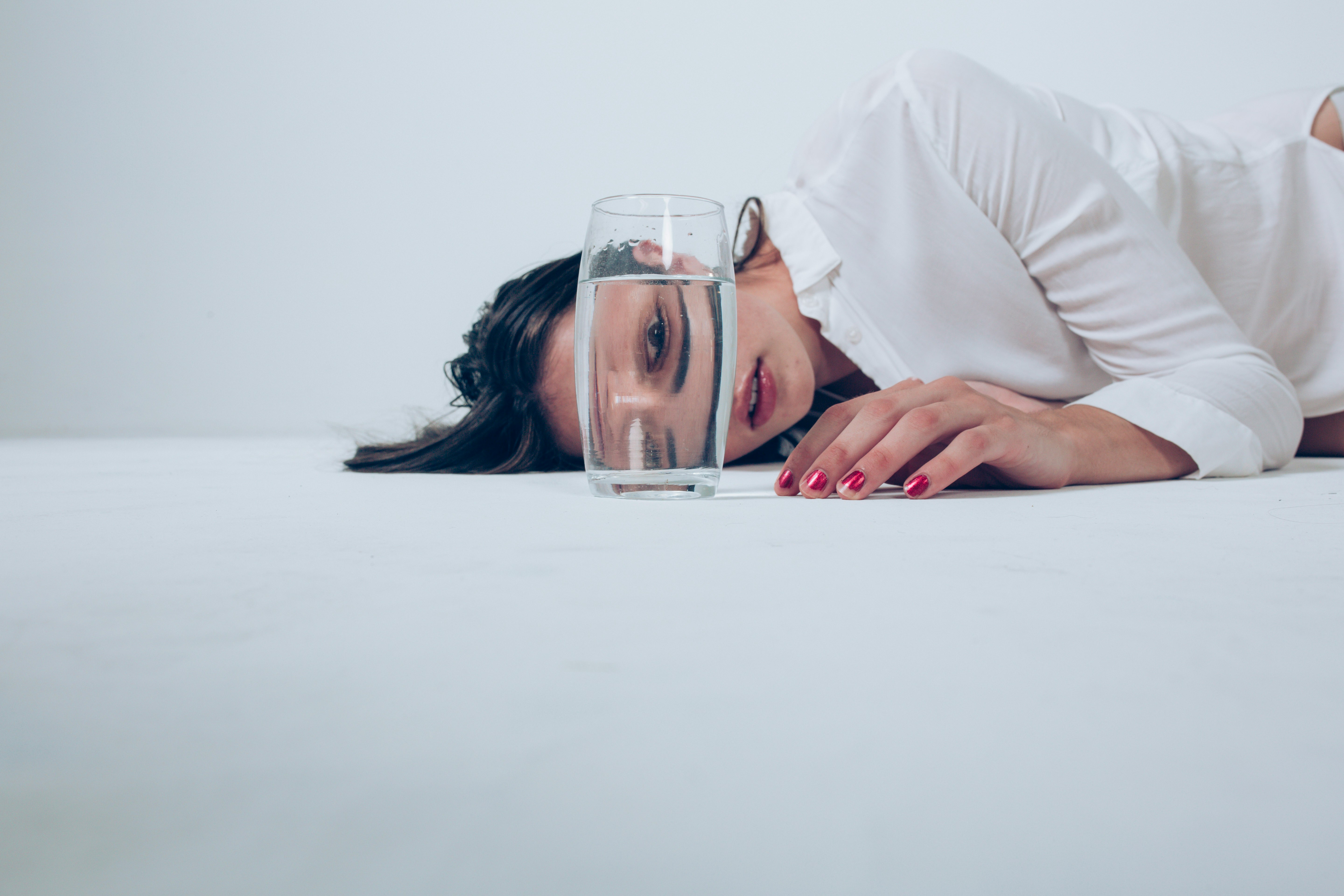 A woman laying on a bed with a glass of water
