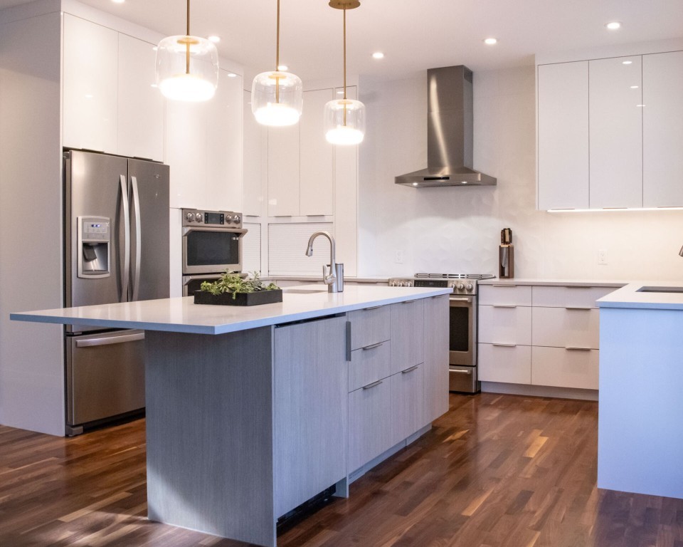 Image of Modern kitchen with island, stainless steel appliances, and white cabinetry designed by KHD Homes for home improvement.