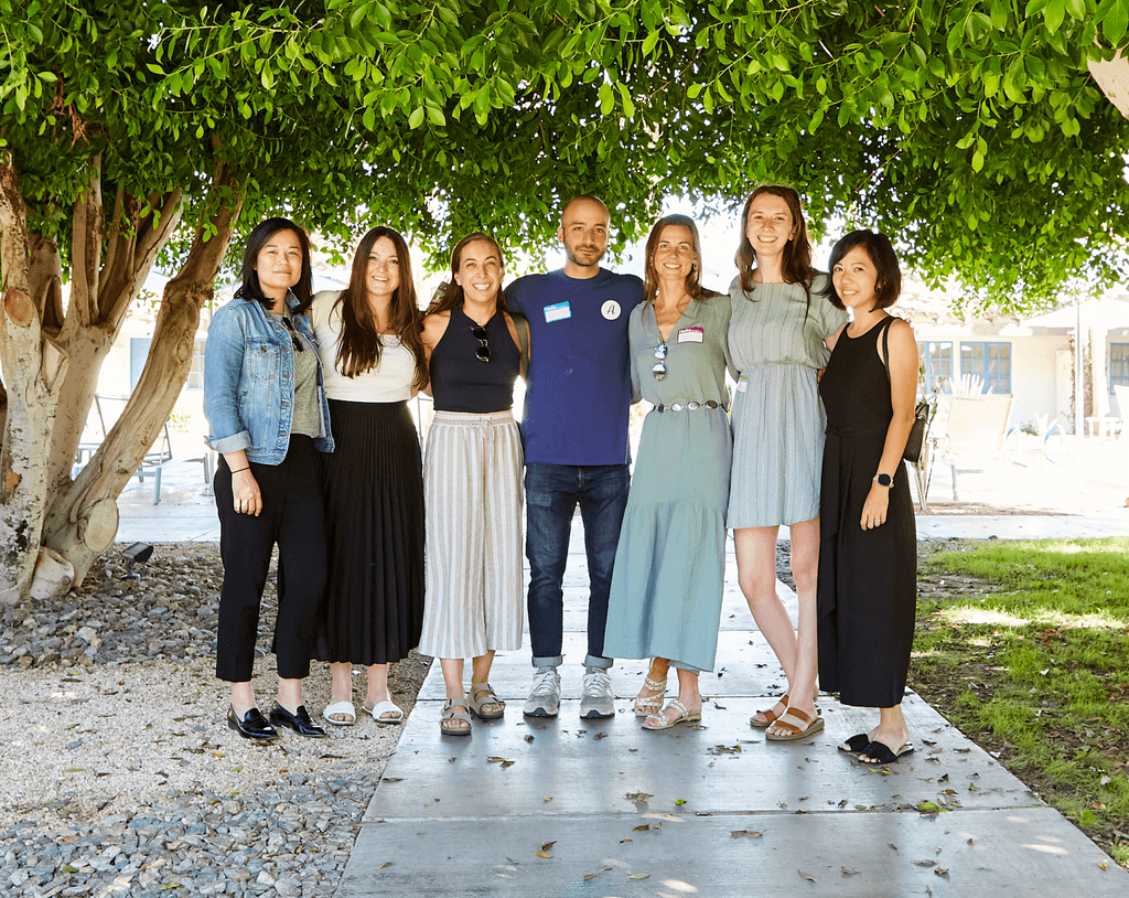 7 people smiling standing under the shade of a tree