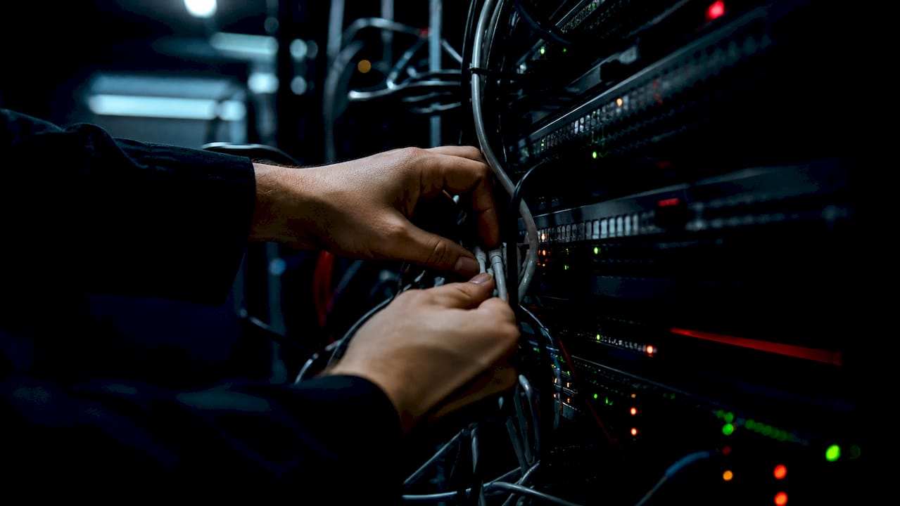 Hands reconnecting network cables in dark server room