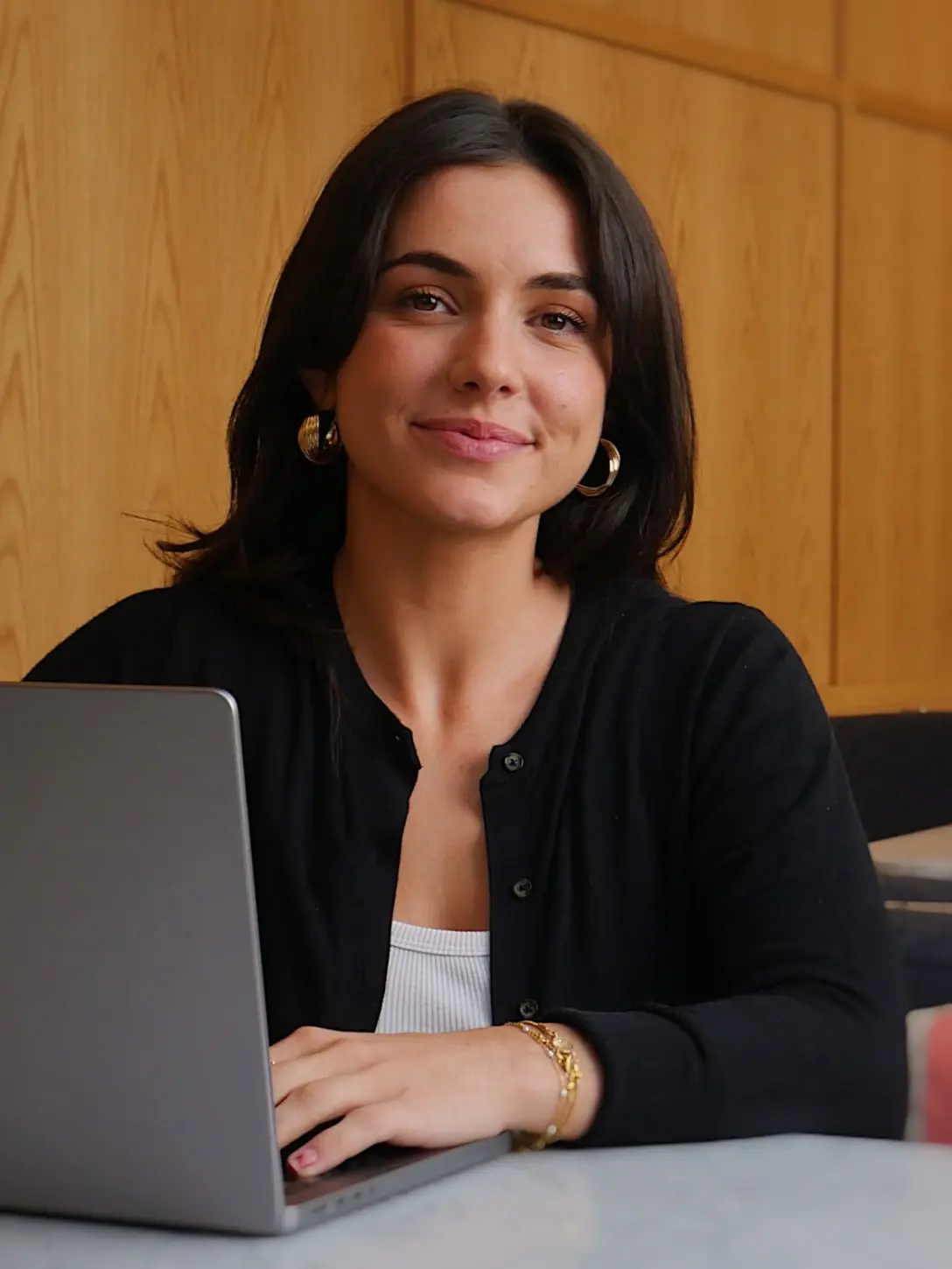 Woman at a laptop, wearing a black cardigan.