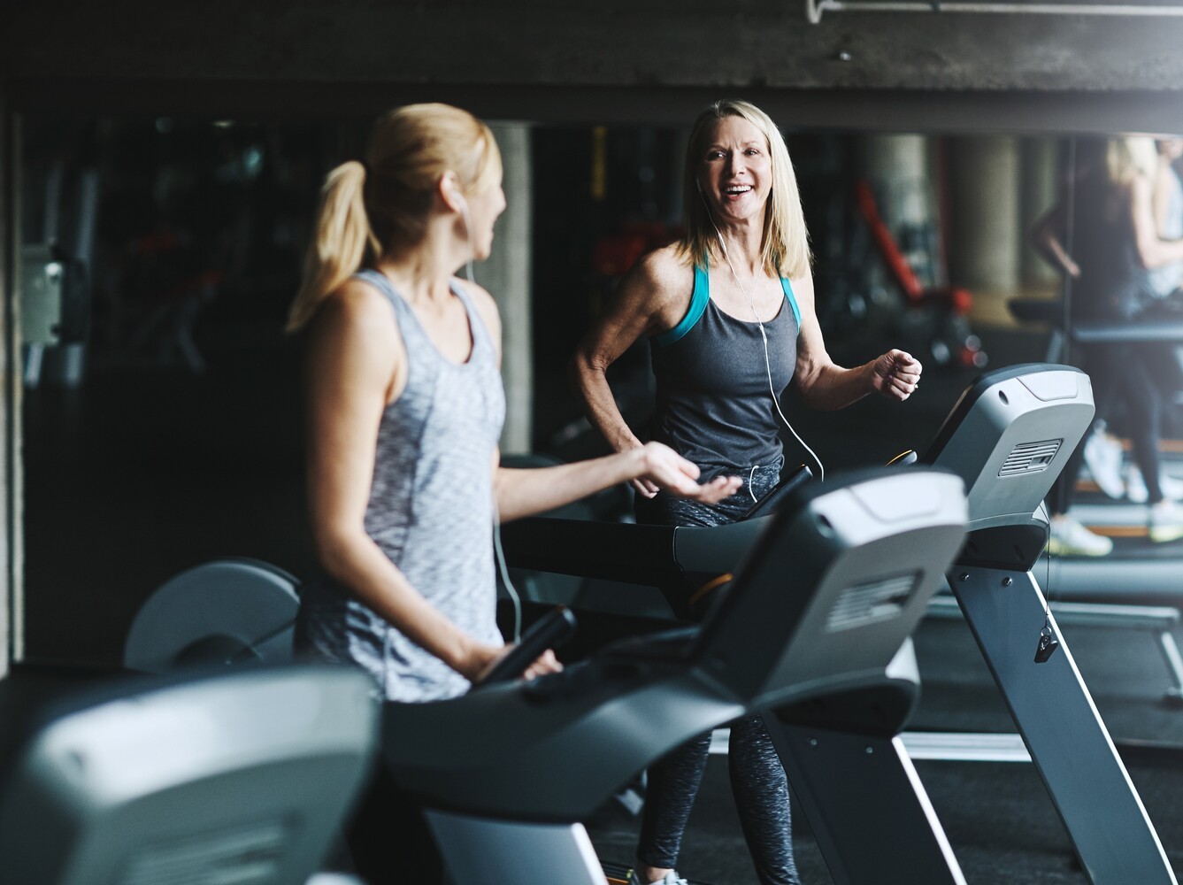 two friends doing their regular weight loss running routine at the gym together on treadmills