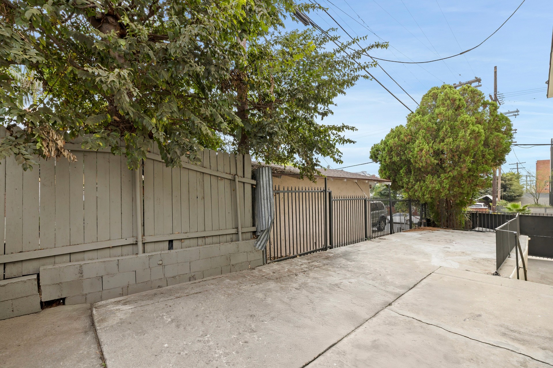 200 N Rampart rear parking pad with gated entry, concrete surface and mature tree along property line.
