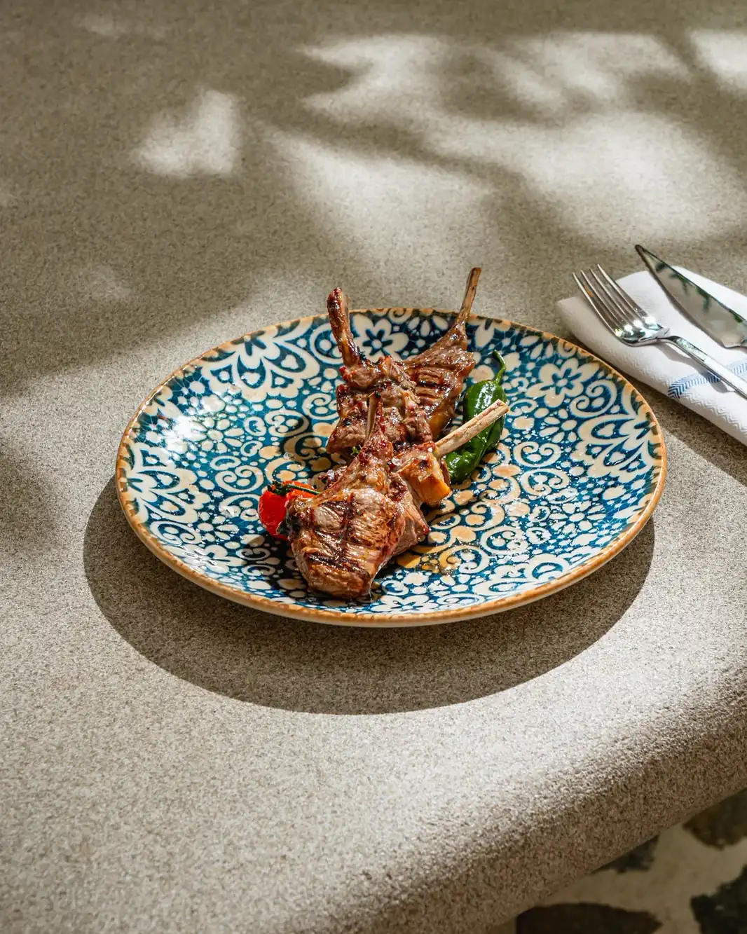 Côtelettes d'agneau grillées servies sur une assiette méditerranéenne.
