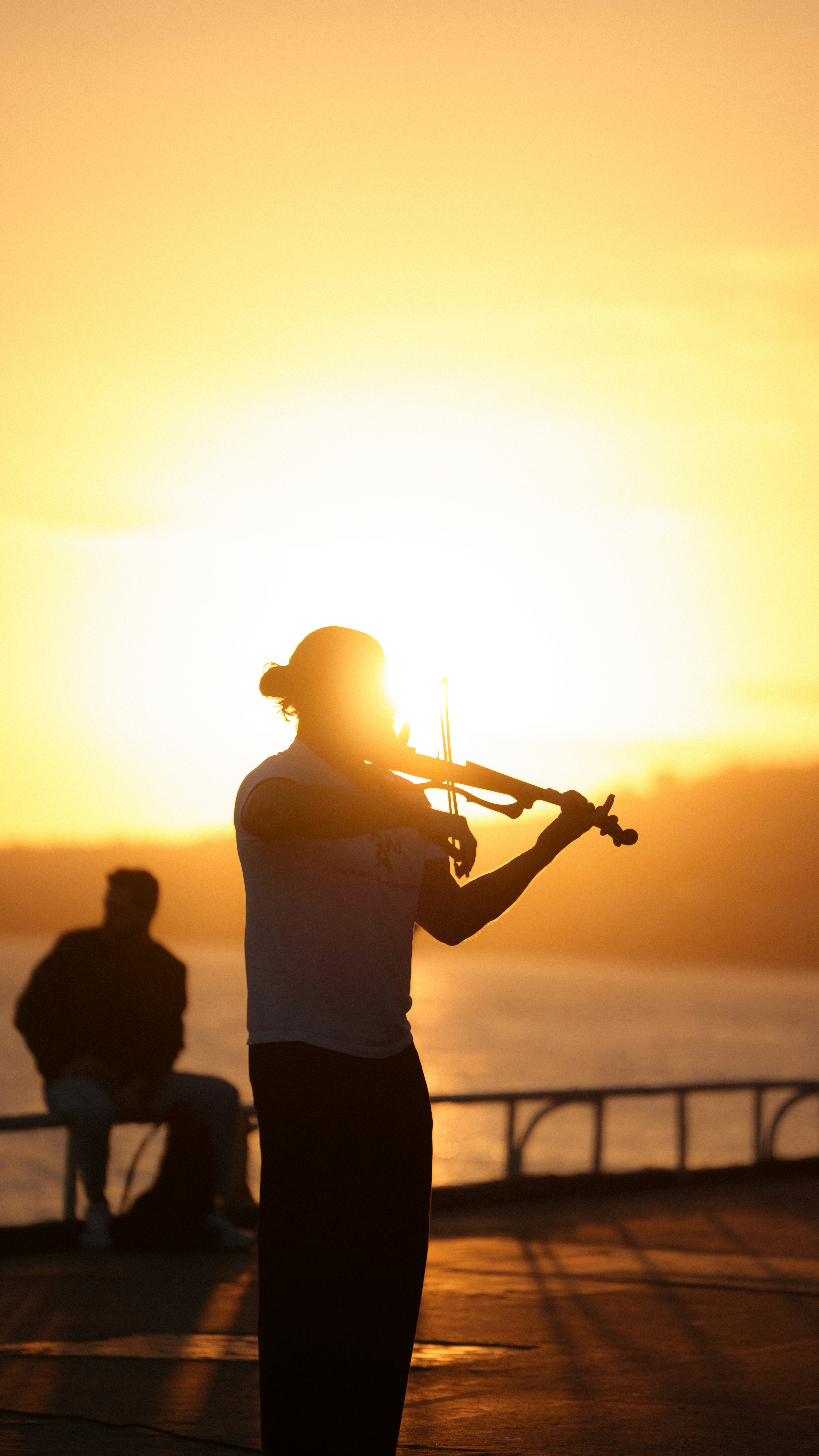 Silhouette of a person playing violin at sunset