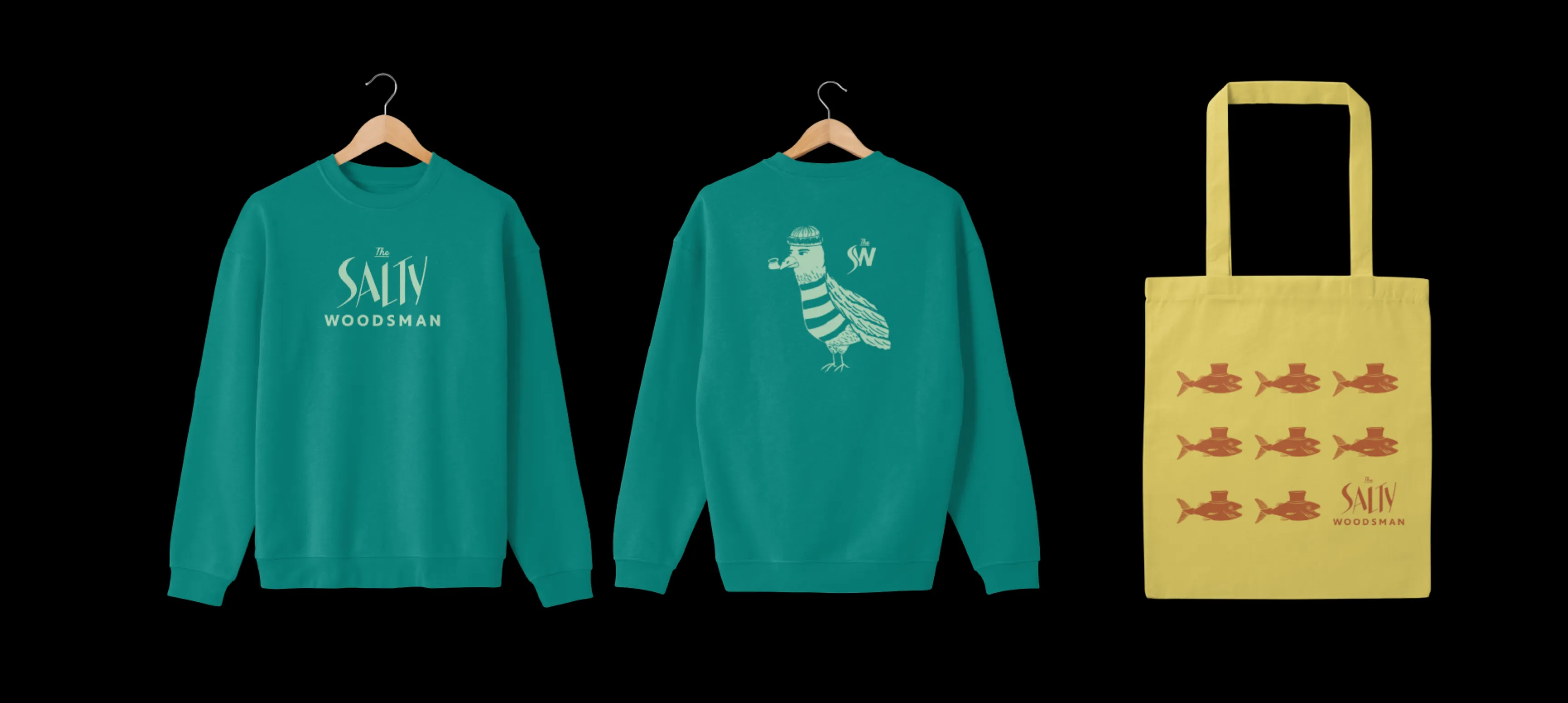 The front and back of a Salty Woodsman teal crewneck sweatshirt. The front has their wordmark and the back has a Seagull wearing a toque smoking a pipe. To the right is a yellow tote bag with a grid of fish illustrations wearing top hats printed in a cedar colour.