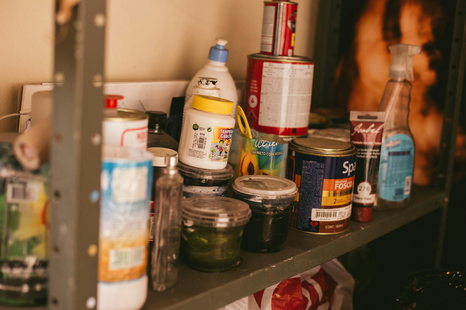 Close-up of organized plastic bins on a shelf labeled with color-coded stickers for markers, scissors, and glue.