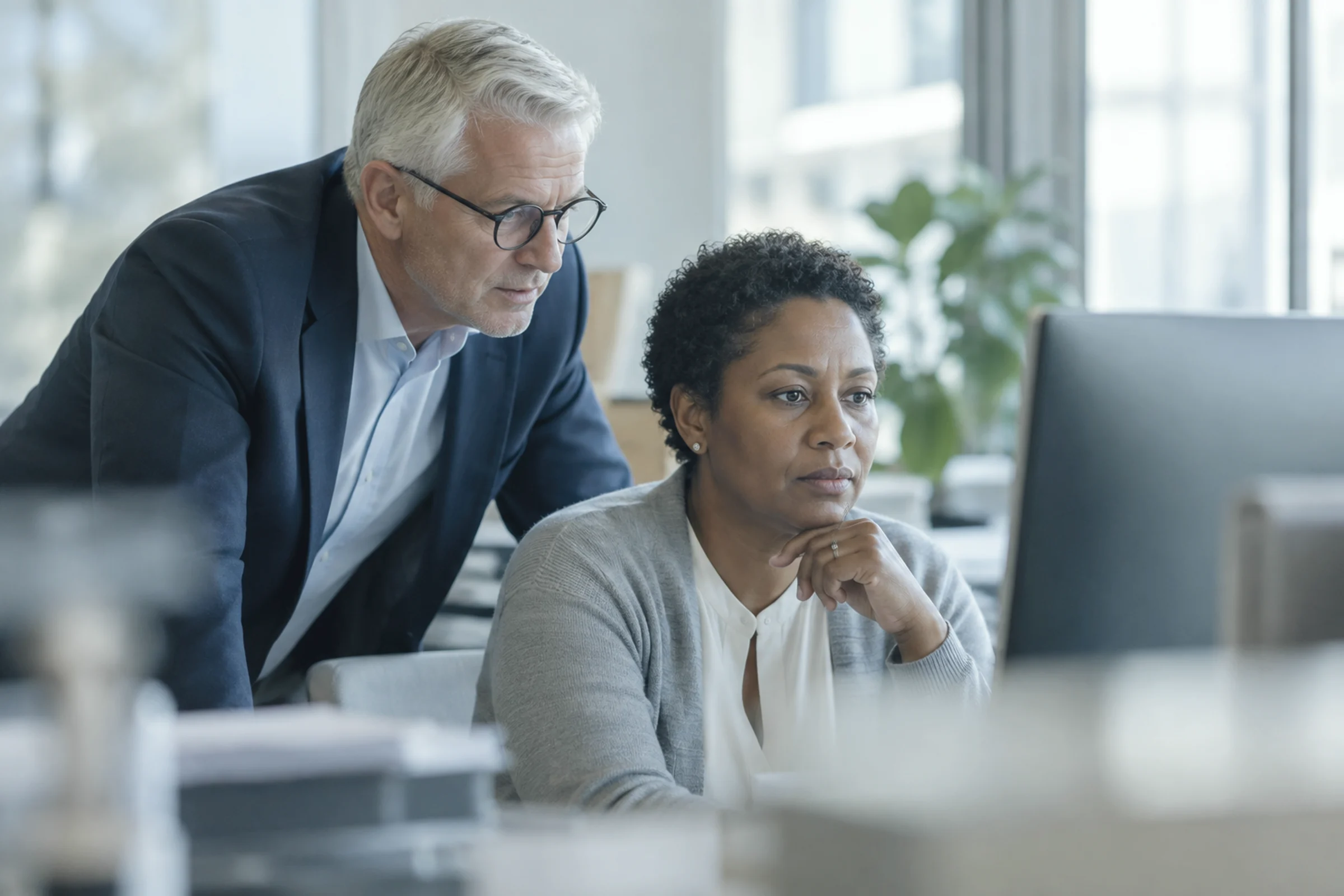 A claims manager and a consultant reviewing a screen together